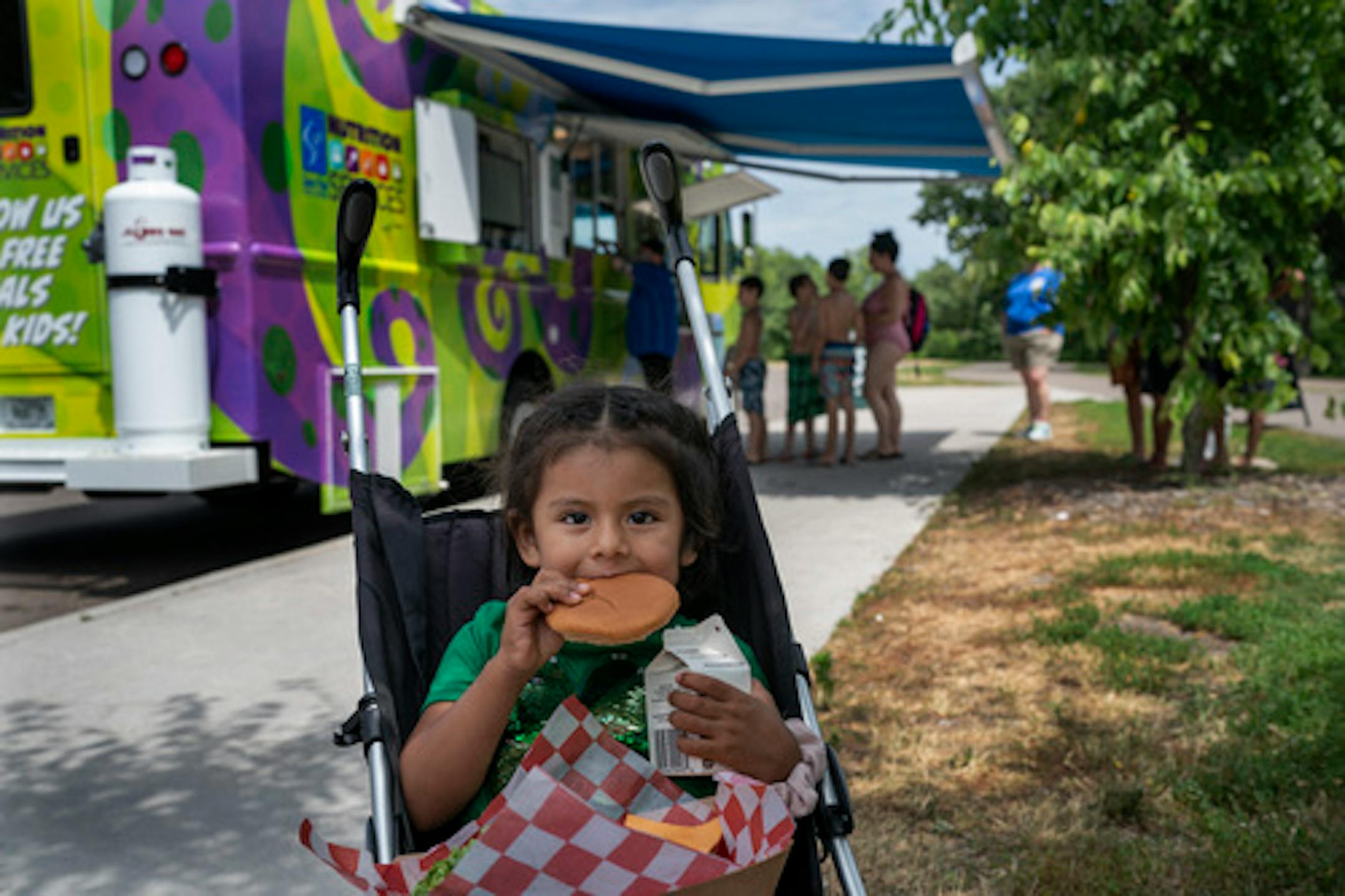 Cristina Sánchez Ortiz, left feeds a her daughter Sabela Bazan Sánchez, 3 a cheeseburger, with fries and milk . The free lunch was from a food truck that delivers meals at Phalen Beach 3 times a week in St. Paul Minn., on Wednesday June 29, 2022.