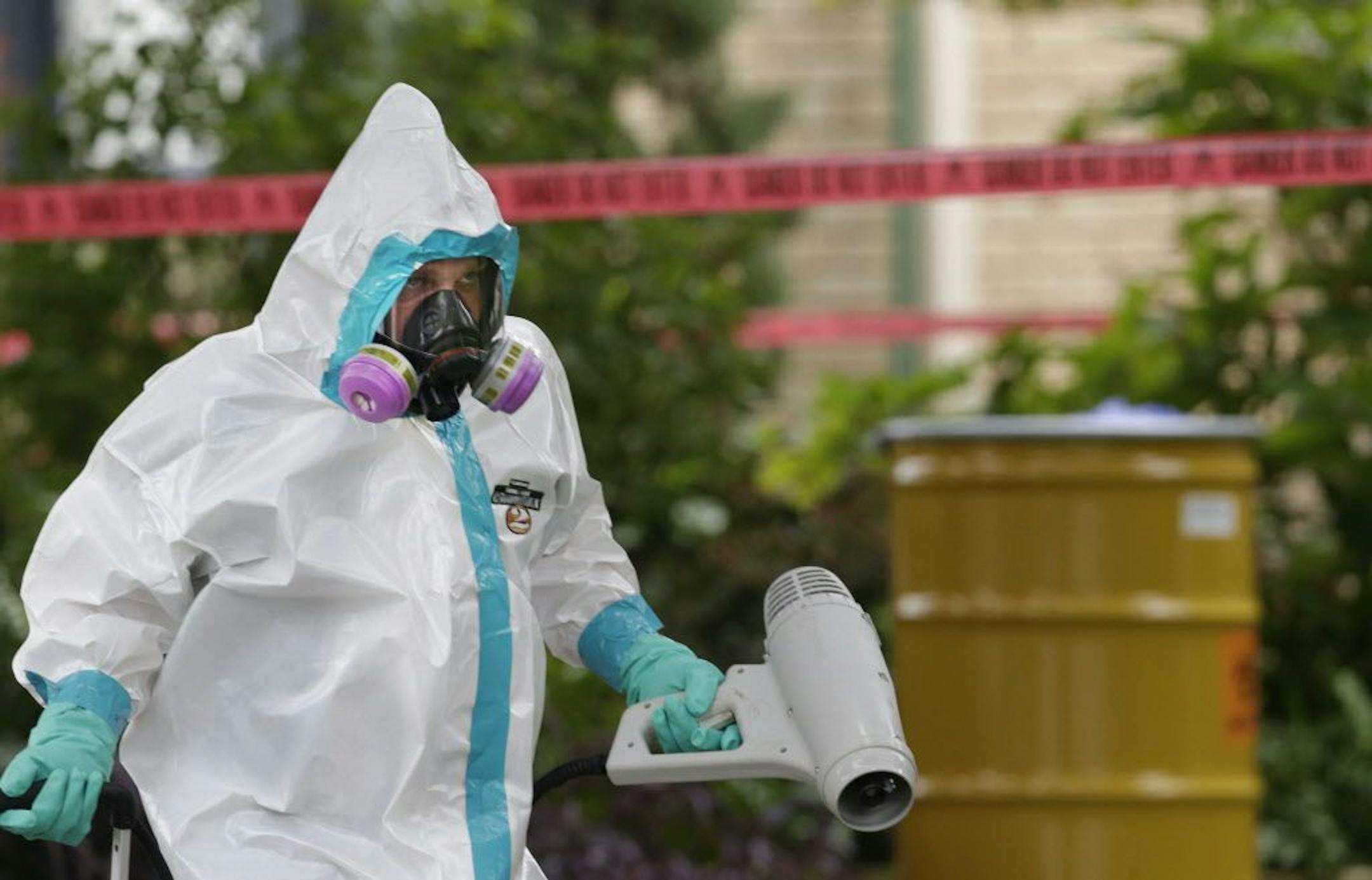 A hazmat worker clean outside the apartment building of a hospital worker who contracted the Ebola virus while caring for a patient, Sunday, Oct. 12, 2014, in Dallas.