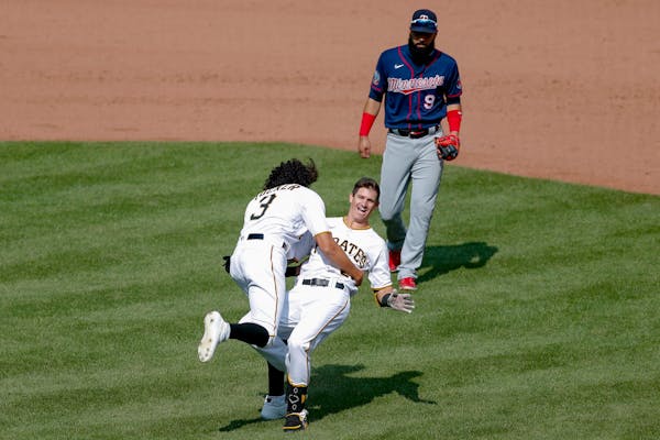 Pittsburgh's Kevin Newman, center, topples over as Cole Tucker celebrates in front of Twins left fielder Marwin Gonzalez, after Newman drove him and B