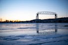 The Duluth aerial lift bridge was reflected in the ice on Lake Superior as the sun set over a frozen Lake Superior in 2021. 