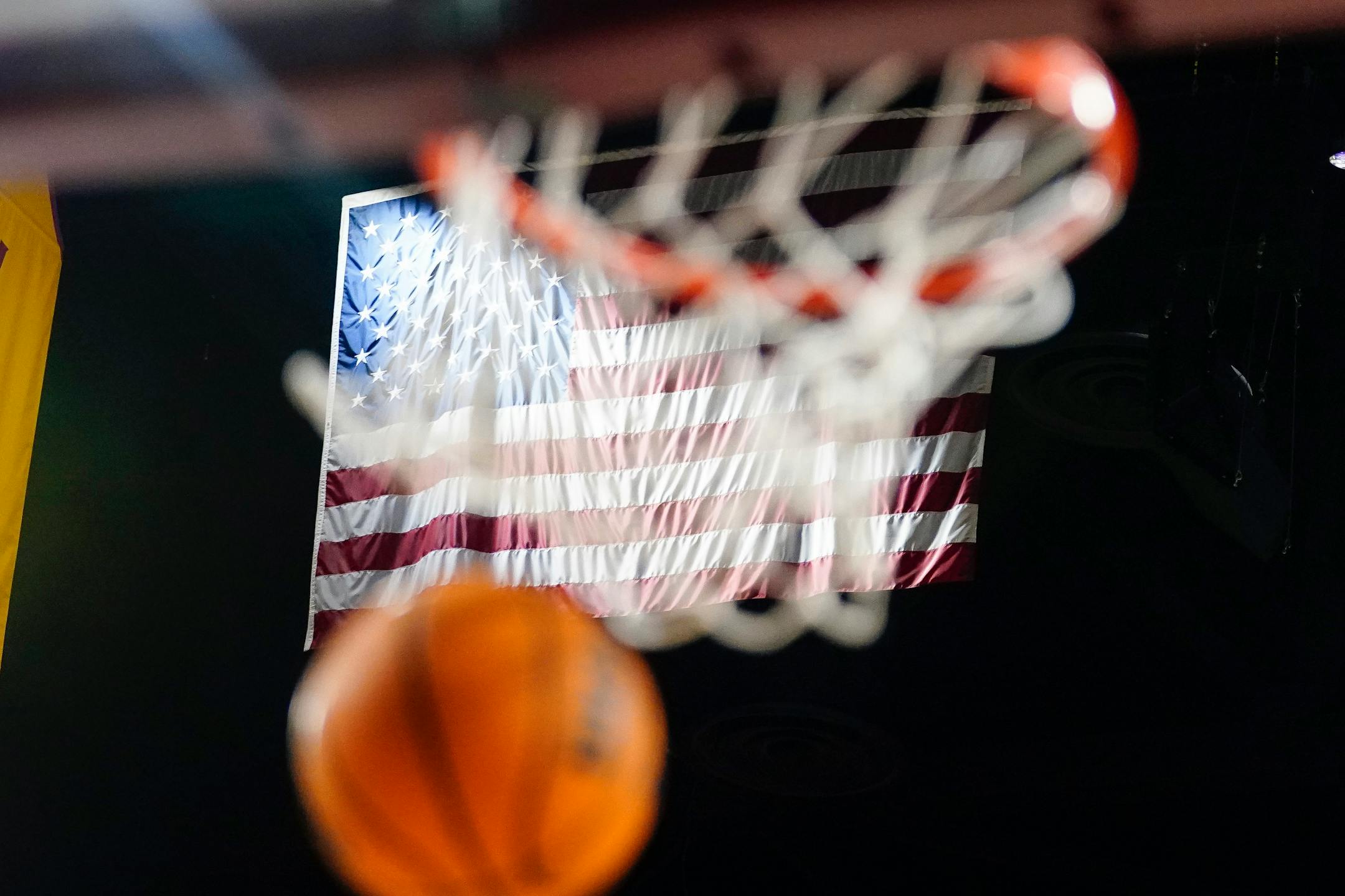 A basketball goes through the hoop in front of the American flag during an NCAA college basketball game between Arizona State and Oregon State, Thursday, Feb. 2, 2023, in Tempe, Ariz. (AP Photo/Darryl Webb)