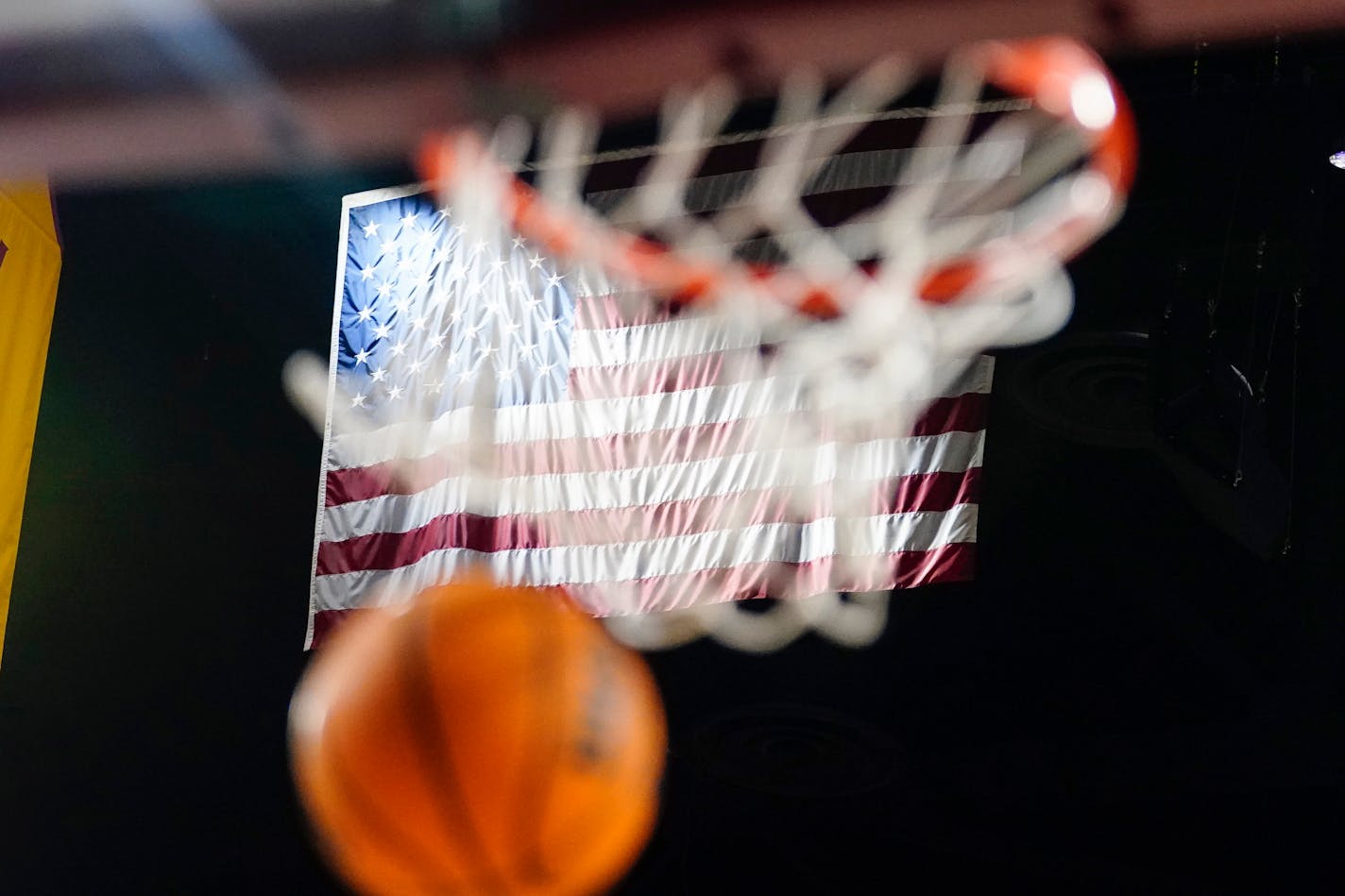 A basketball goes through the hoop in front of the American flag during an NCAA college basketball game between Arizona State and Oregon State, Thursday, Feb. 2, 2023, in Tempe, Ariz. (AP Photo/Darryl Webb)