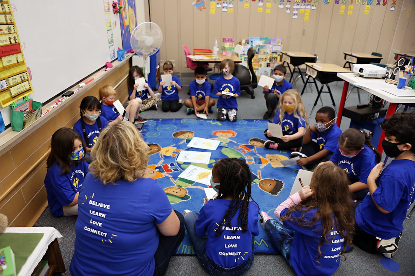 Elementary students sit in a circle with their teacher.