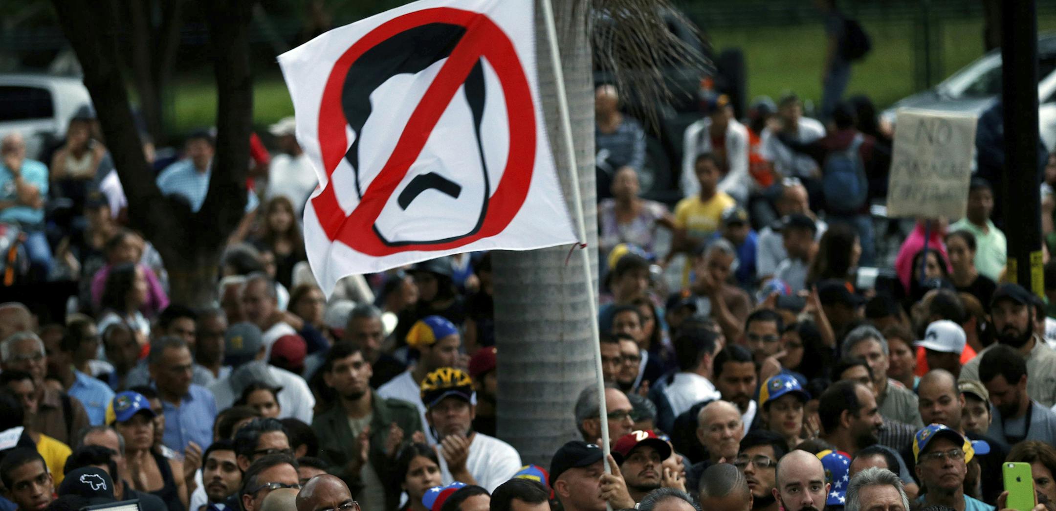 An anti-government demonstrator waves a flag against Venezuela's President Nicolas Maduro during a vigil in honor of those who have been killed during clashes between security forces and demonstrators in Caracas, Venezuela, Monday, July 31, 2017. Many analysts believe Sunday's vote for a newly elected assembly that will rewrite Venezuelaís constitution will catalyze yet more disturbances in a country that has seen four months of street protests in which at least 125 people have died. (AP Ph