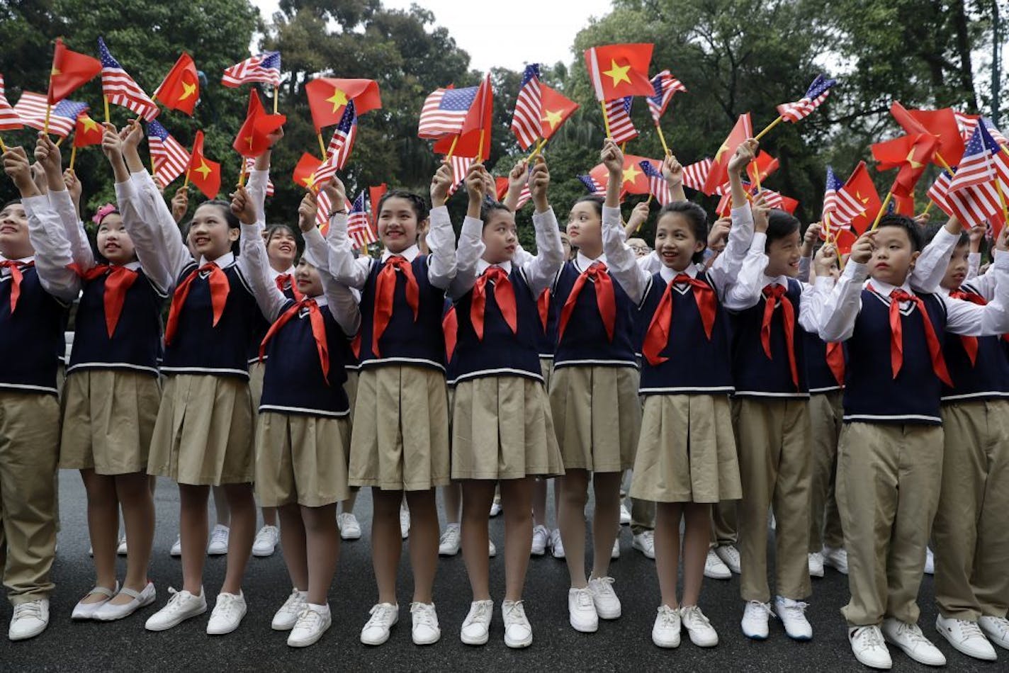 Children wave flags before President Donald Trump arrives to meet Vietnamese President Nguyen Phu Trong at the Presidential Palace, Wednesday, Feb. 27, 2019, in Hanoi.