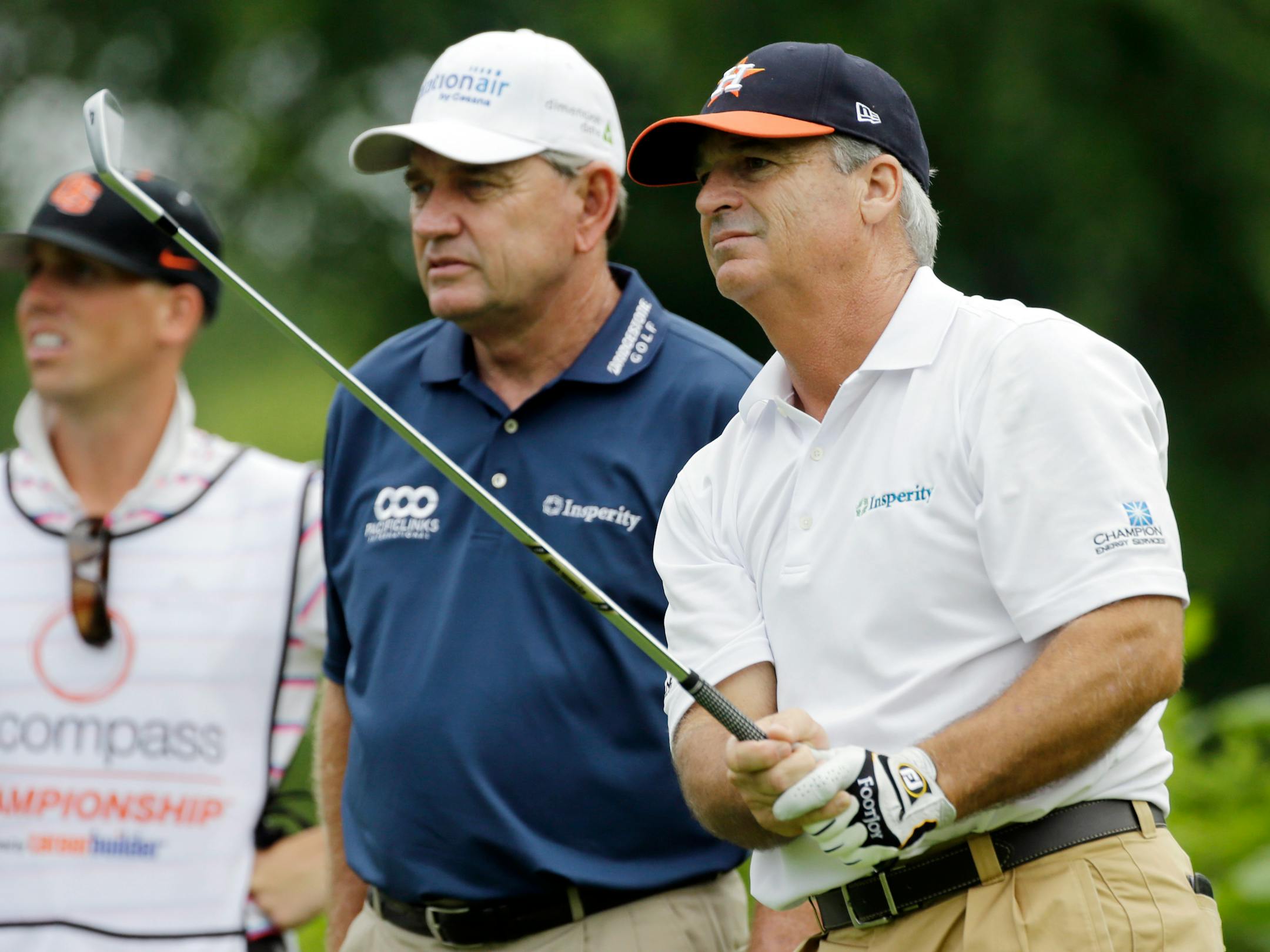 CORRECTS TO FOURTH HOLE, NOT SECOND HOLE - Blaine McCallister, right, tees off on the fourth hole, as Nick Price, center, looks on during the first round of the Encompass Championship golf tournament on Friday, June 21, 2013, in Glenview, Ill. (AP Photo/Nam Y. Huh)