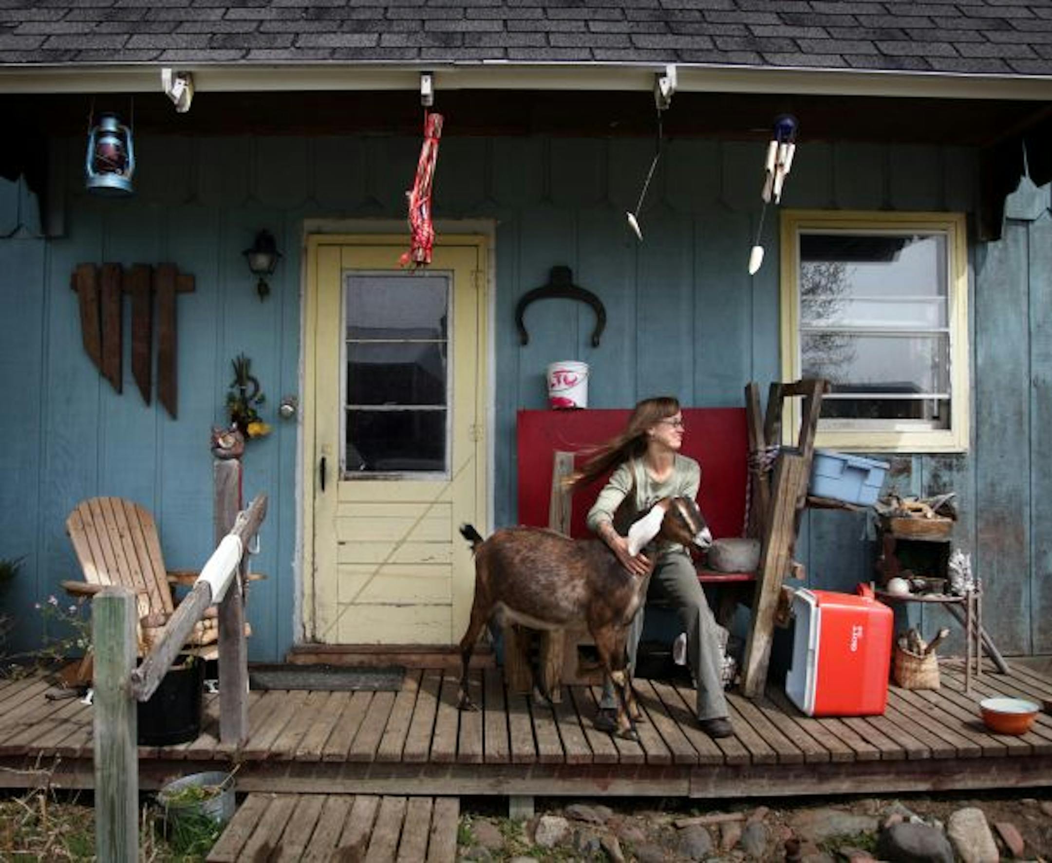 Khaiti Khaleck hangs out on her farmhouse porch with one of her goats, Catalpa. She raises crops and animals on a 1.8-acre plot near Osceola, Wis.