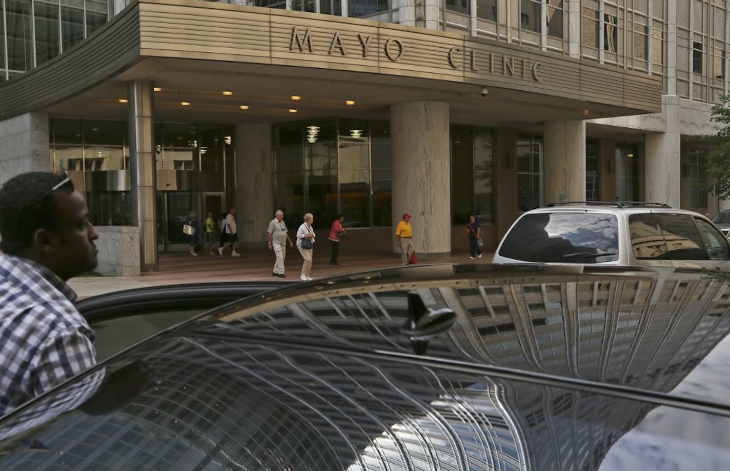 A row of black luxury sedans was parked outside the Mayo Clinic Thursday, August 8, 2013, including this one that reflected the top of the building.