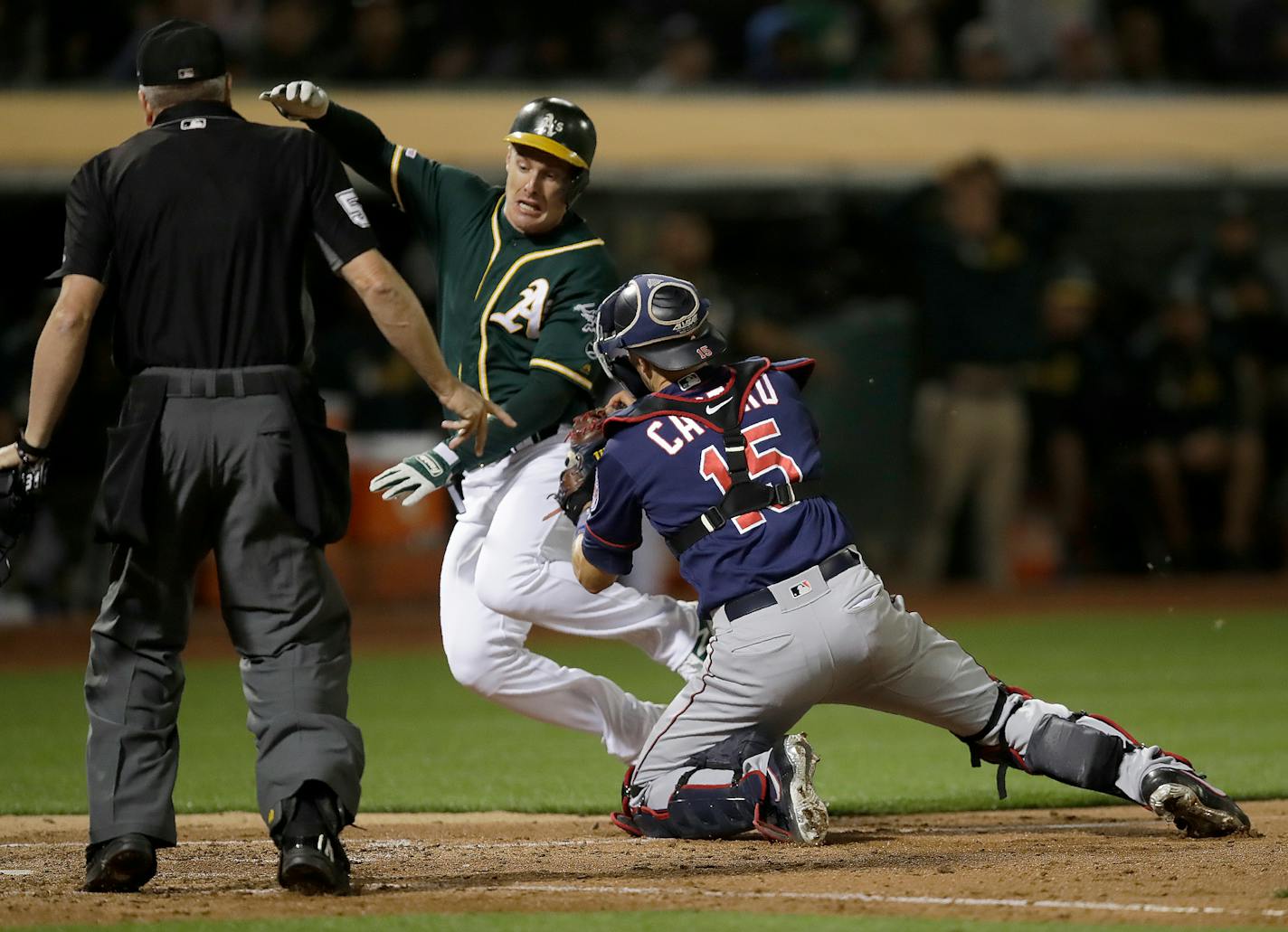 Minnesota Twins catcher Jason Castro, right, tags out Oakland Athletics' Mark Canha at home plate in the fifth inning of a baseball game Tuesday, July 2, 2019, in Oakland, Calif. (AP Photo/Ben Margot)