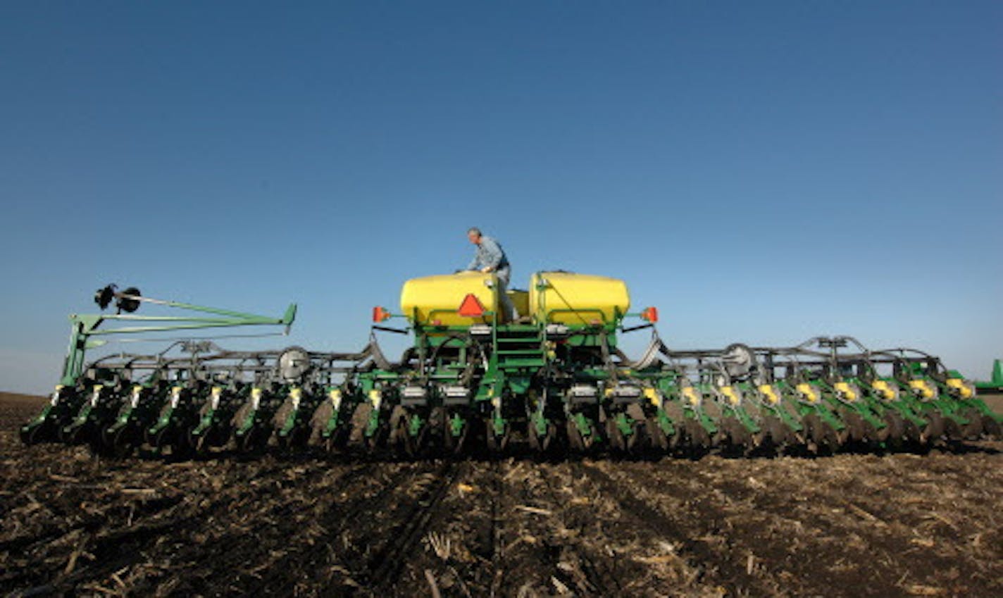 MATT MCKINNEY &#xef; mmckinney@startribune.com -- Willmar, Minn. -- ] Cliff Larson Jr. checks the seed levels in his John Deere planter while seeding a soybean field near Willmar. The planter's air powered system blows seeds to each of 24 rows.