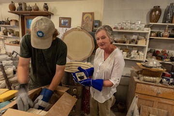 New London potter Bill Gossman, left, and Janet Olney, executive director of the Willmar Area Arts Council, pull newly fired tiles from his kiln. The 