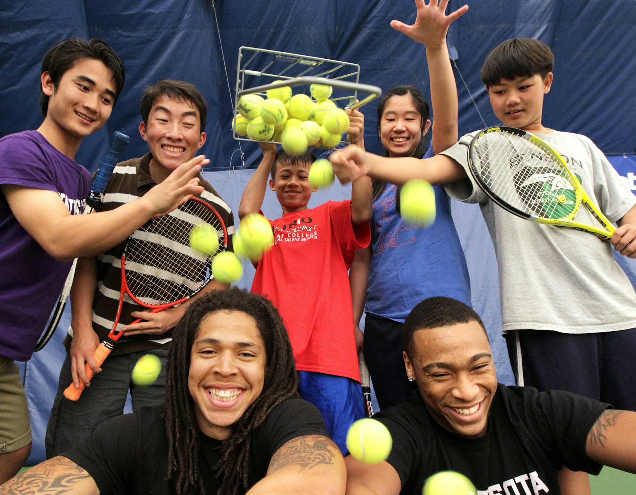 Wells Academy students drop a basket of balls onto volunteers Derrick Wells, left, and Cedric Thompson at Fred Wells Tennis and Education Center in St. Paul May 5, 2013. The Gopher football players play tennis with the students and hope to encourage them in both academic and athletic pursuits. (Courtney Perry/Special to the Star Tribune)