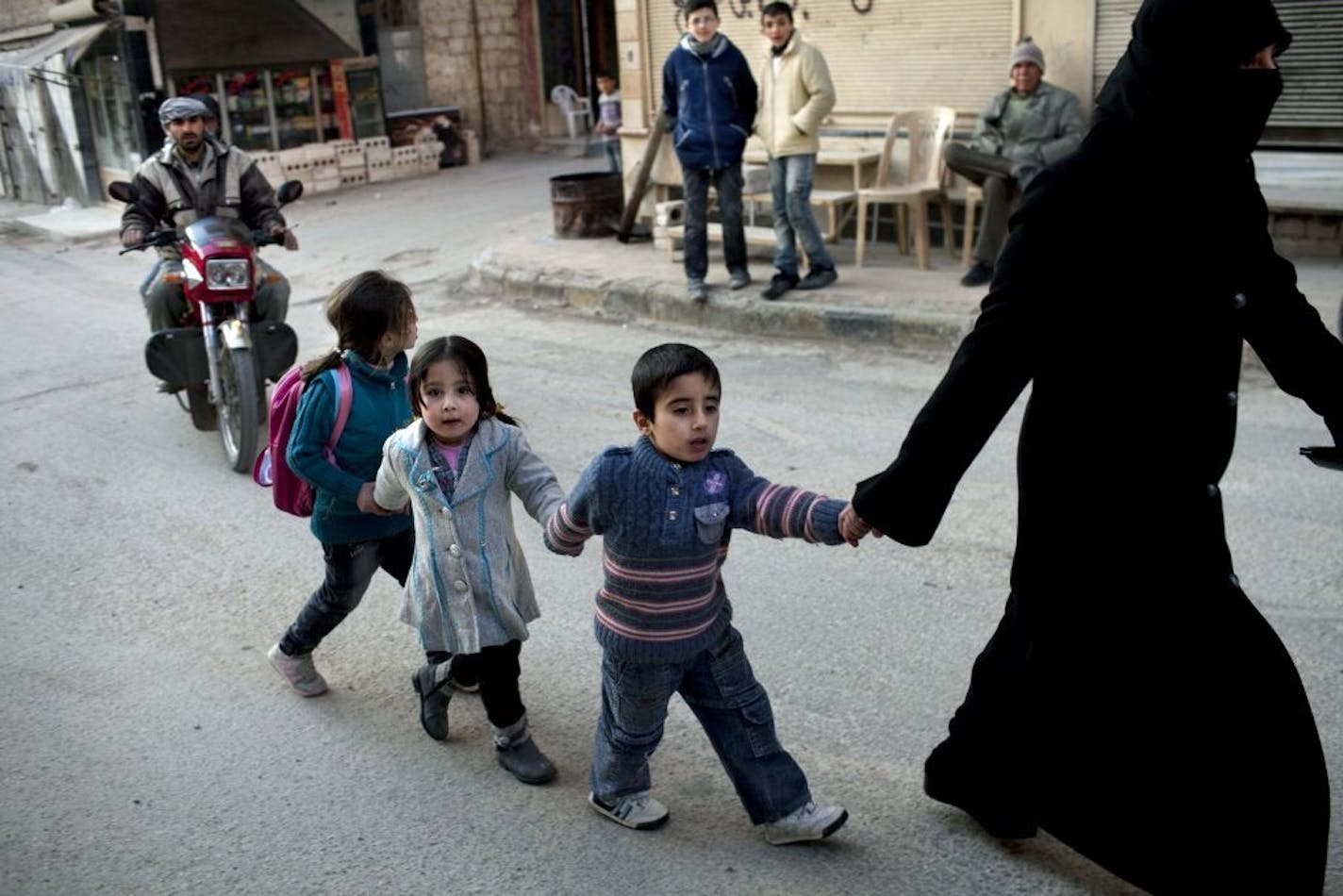 A woman walks with children in Kafar Taharim, north Syria, Saturday, Feb. 25, 2012. The town of Kafar Taharim is under control of the Free Syrian Army for the past month, and people continue a normal life due to the lack of combat with government military forces.