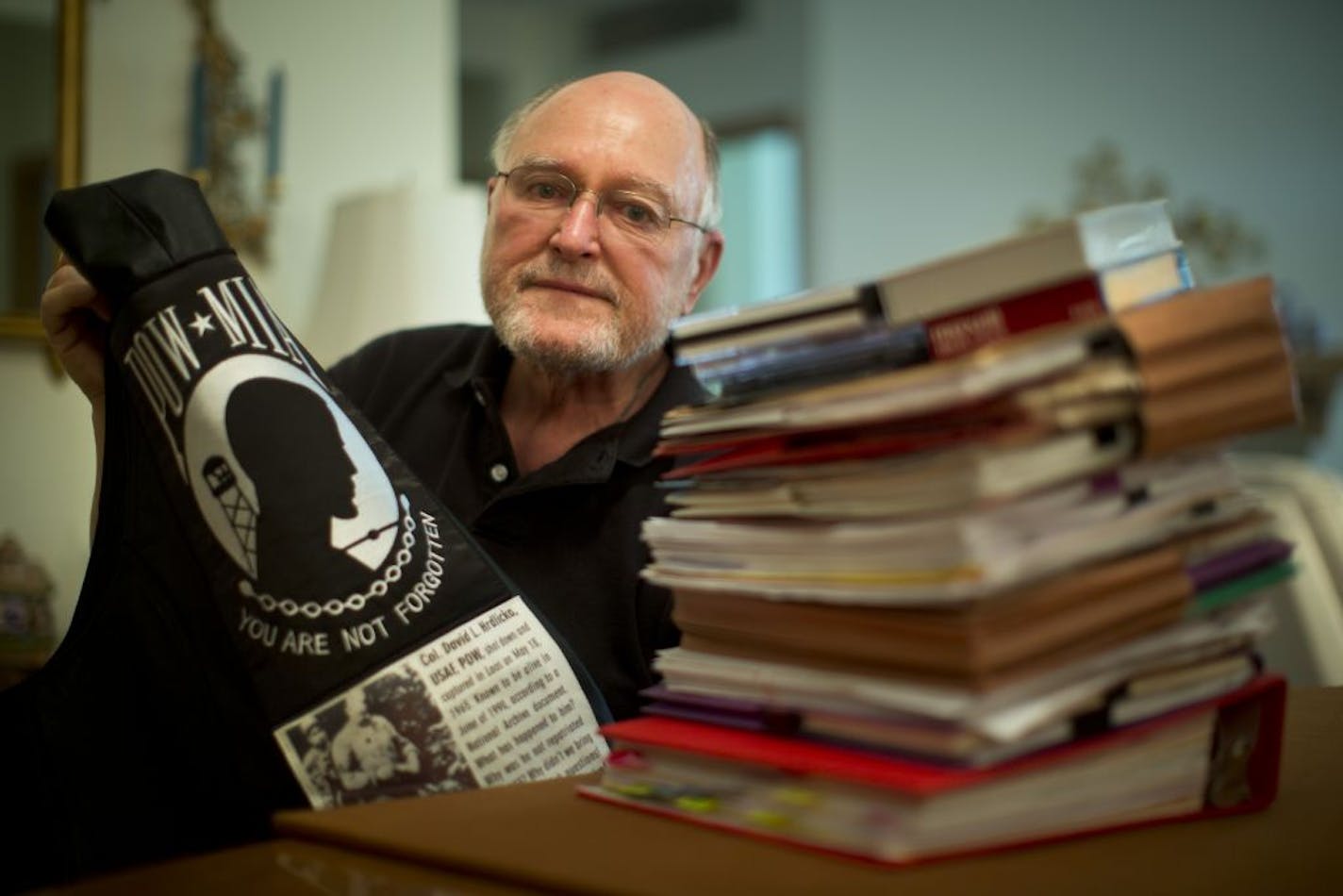 Jerry Streeter, with a POW/MIA banner and a stack of documents he has researched, has become a passionate advocate for finding out what happened to high school classmate David Hrdlicka, who was shot down over Laos in 1965.