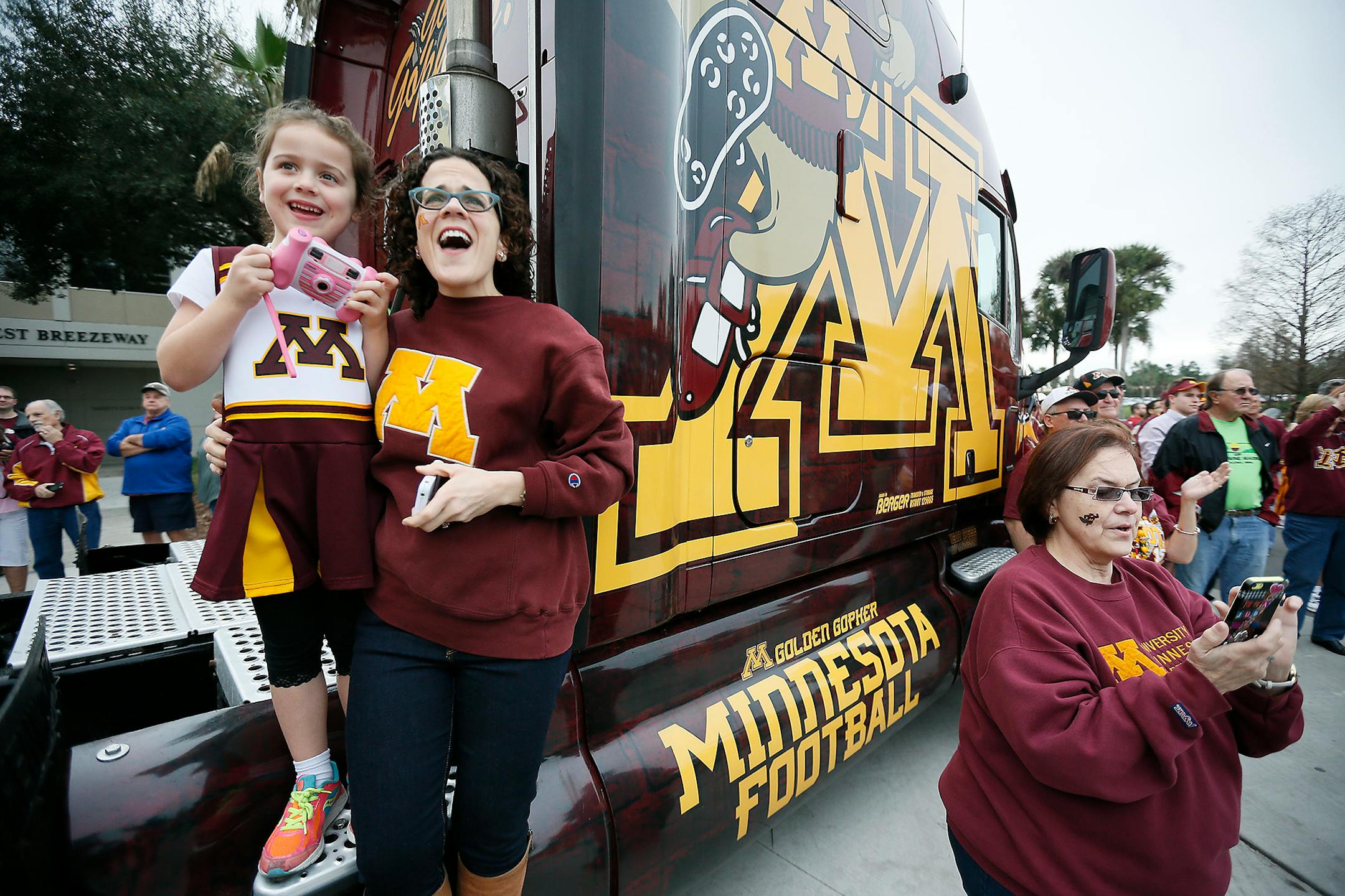 Amy Dostral Dauer, center, and her daughter Eleanor, 7, left, and Judy Dostal right, greeted the team as they made their way off the buses and into Citrus Bowl Stadium, Thursday, January 1, 2015 in Orlando, FL. ] (ELIZABETH FLORES/STAR TRIBUNE) ELIZABETH FLORES � eflores@startribune.com