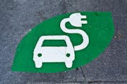 Electric car sign, charging station, green sign painted on street. Electric vehicle sign with car and plug, uploading place.