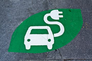 Electric car sign, charging station, green sign painted on street. Electric vehicle sign with car and plug, uploading place.