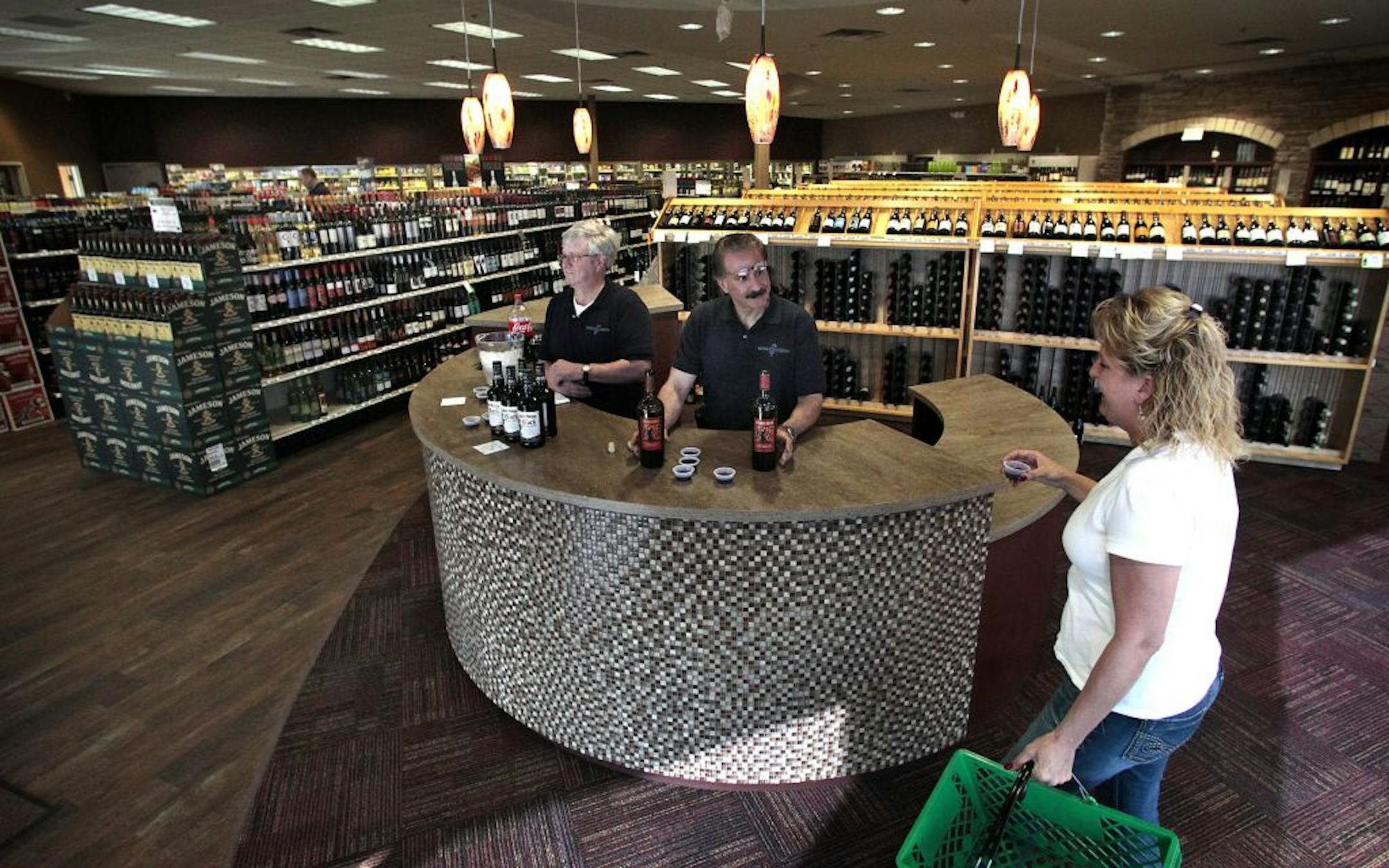 Victoria McNamara of St. Louis Park tasted a merlot while shopping at Edina Liquors recently while store workers Don Hultmann, left, and Joe Ruiz greeted customers as they entered the store.