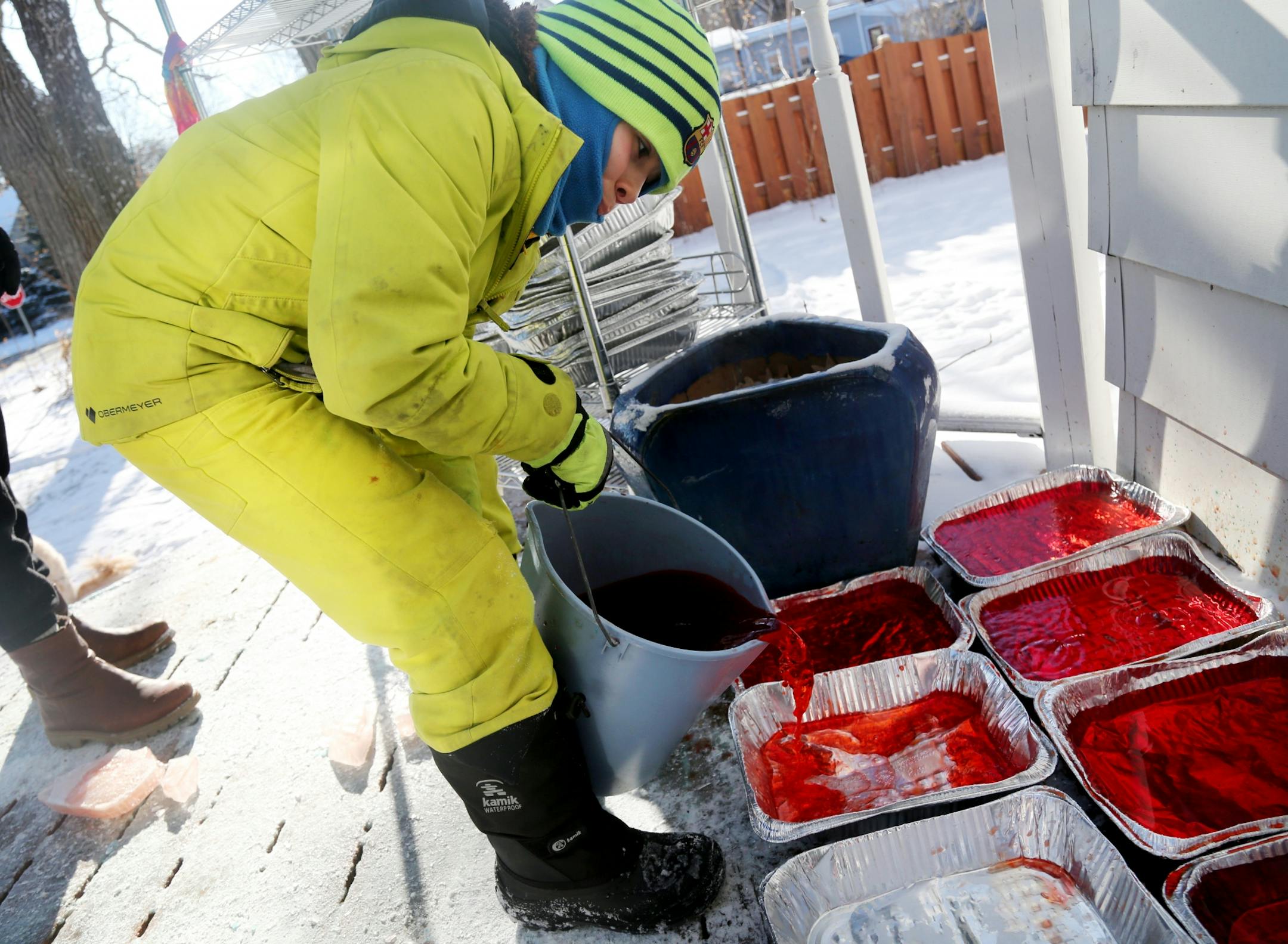 Martha Palm, her family and some former students of hers will be working on the multi-colored igloo they are building at the Palms' south Minneapolis home and seen Saturday, Dec. 30, 2017, in Minneapolis, MN. Here, a mixture of snow and water was mixed together to form the mortar to bond the ice blocks together. Arlo Zirps, 10, mixed red food color with water before pouring the water into aluminum baking trays to form the frozen igloo blocks.