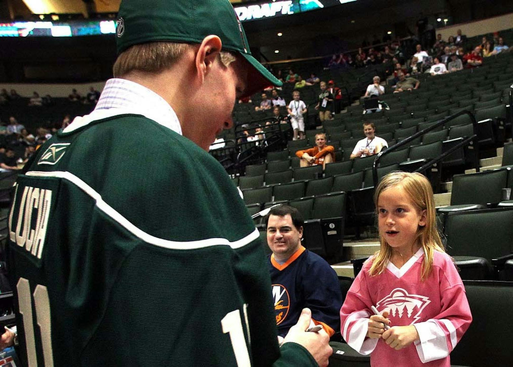 Wayzata High School's Mario Lucia, son of Gophers hockey coach Don Lucia, signed one of his first autographs as a member of the Wild organization on Saturday at Xcel Energy Center. Emma Hoen, 7, of Maple Grove appears to be looking forward to the day Lucia might be in the Wild lineup. Lucia has a year of high school remaining and will decide soon where he will play his senior season. He also will choose between the Gophers — and playing for his dad — Notre Dame and Colorado College.