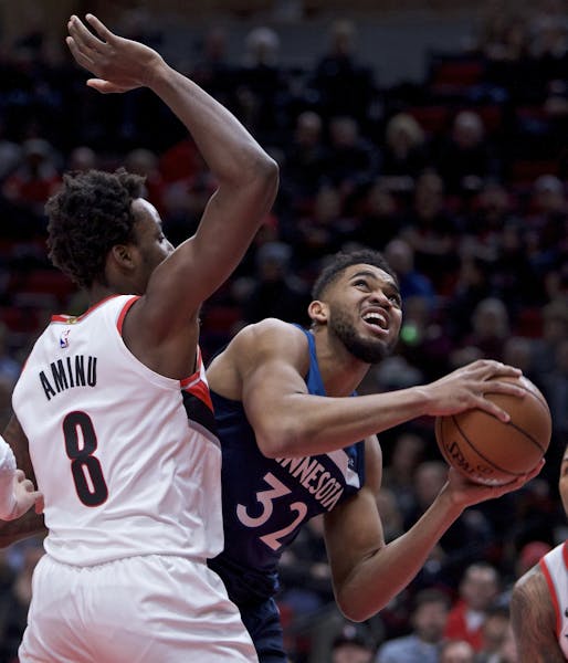 Minnesota Timberwolves center Karl-Anthony Towns, right, drives to the basket past Portland Trail Blazers forward Al-Farouq Aminu during the first hal
