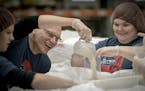 The Current's Mark Wheat, left, shared a laugh with Emma Strub as they joined listeners and other staff help pack rice at Second Harvest Heartland, Th