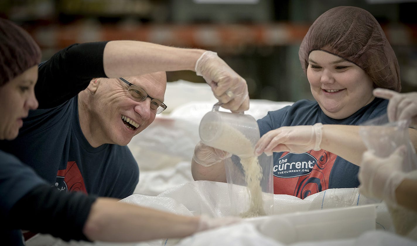 The Current's Mark Wheat, left, shared a laugh with Emma Strub as they joined listeners and other staff help pack rice at Second Harvest Heartland, Thursday, November 16, 2017 in Golden Valley, MN. ] ELIZABETH FLORES &#xef; liz.flores@startribune.com