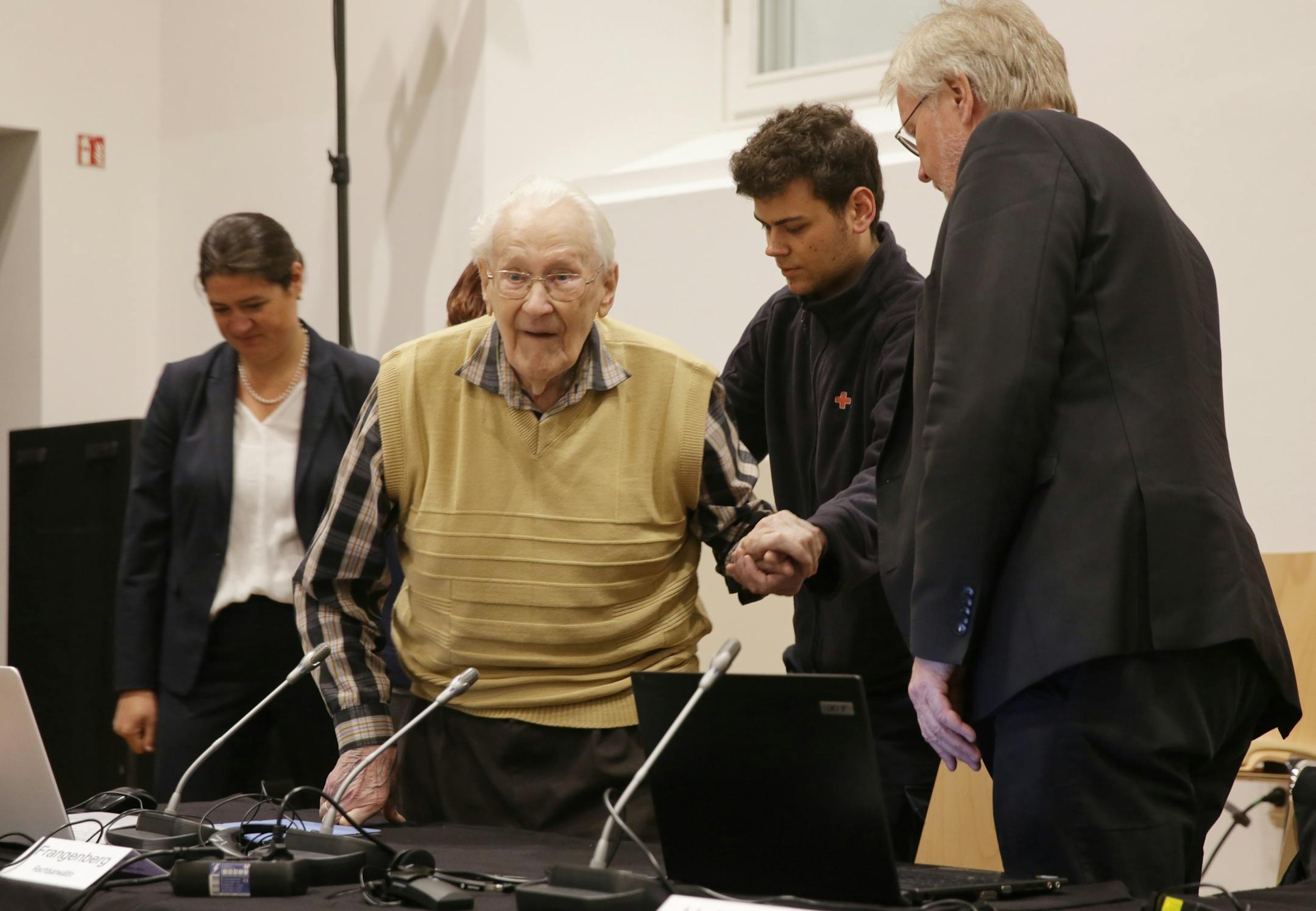 Defendant Oskar Groening is led to his seat prior to the court session in his trial on accessory to murder in the court in Lueneburg, northern Germany, Wednesday, May 13, 2015. The former SS sergeant is being tried on 300,000 counts of accessory to murder and faces a possible sentence of three years to 15 years if convicted. Prosecutors argue his role sorting prisoners' stolen valuables, which he admits, helped Auschwitz function.