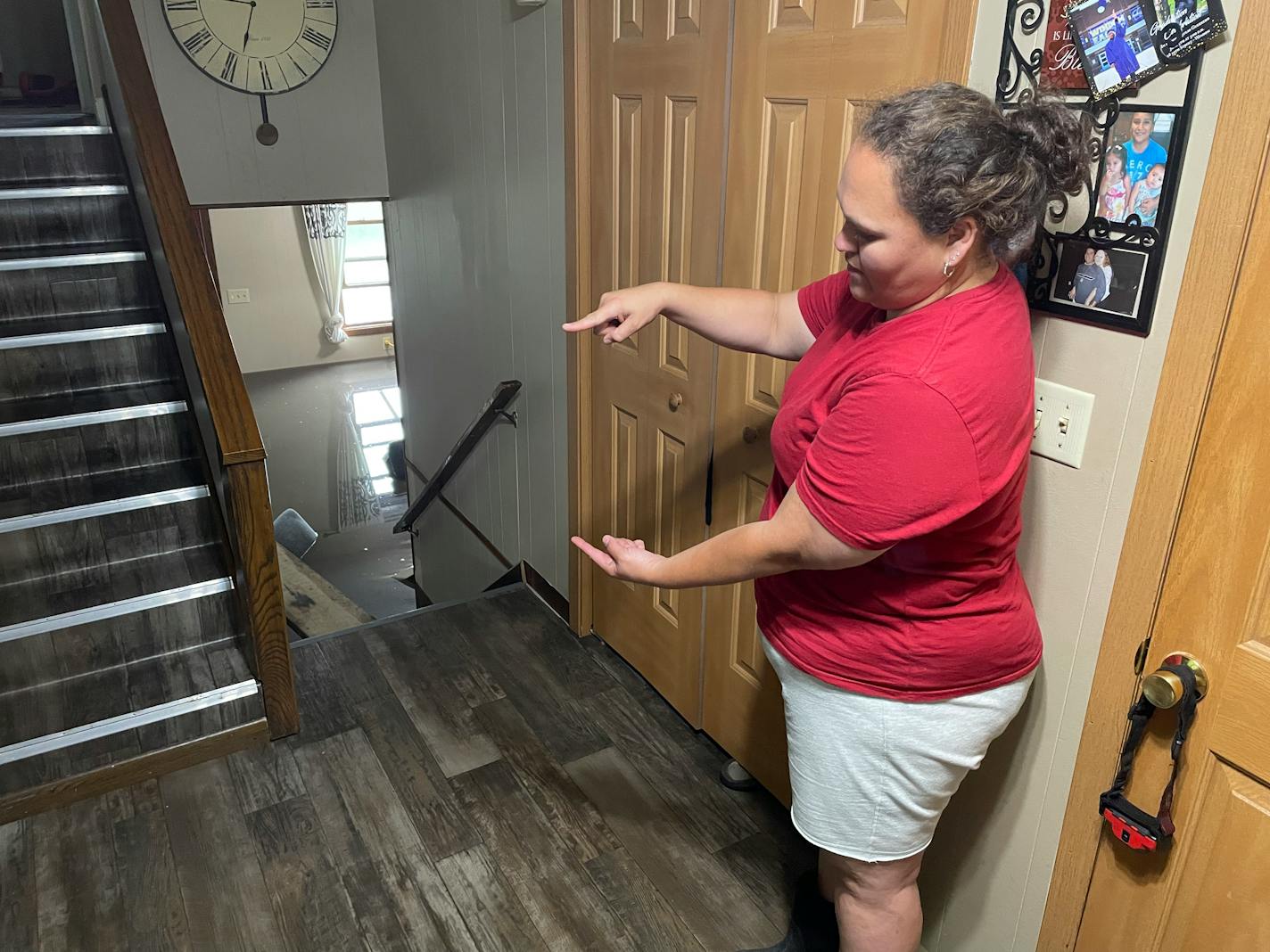 A woman makes a gesture indicating more than a foot of water entered her home after a flood.