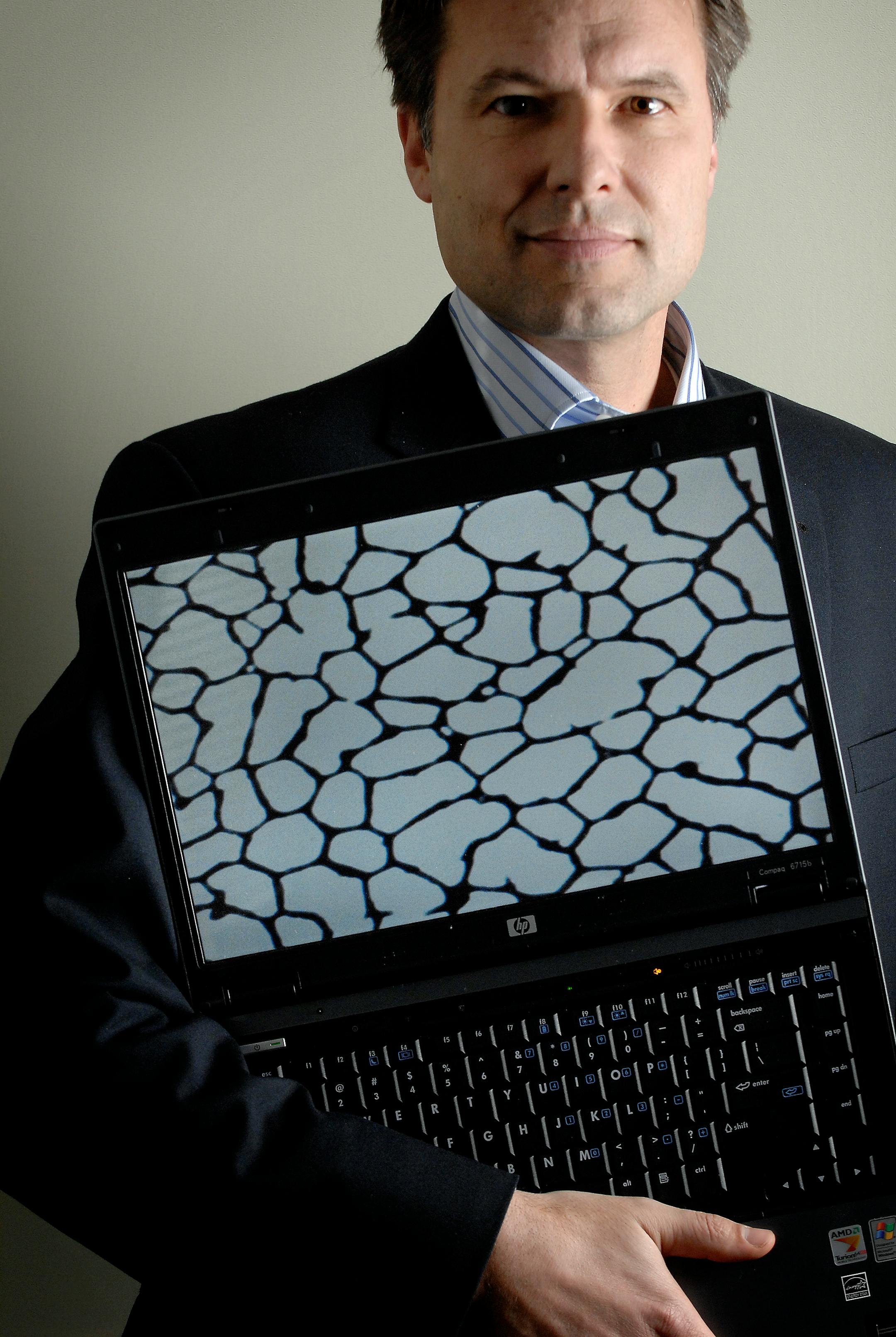 Cima NanoTech CEO Jon Brodd showed a microscopic image of a product being developed by his company of nanoparticles, which self-assemble into a transparent coating. The product is being developed for plasma displays, touch screens and solar cells. The holes average about 100 microns, about the diameter of a human hair.