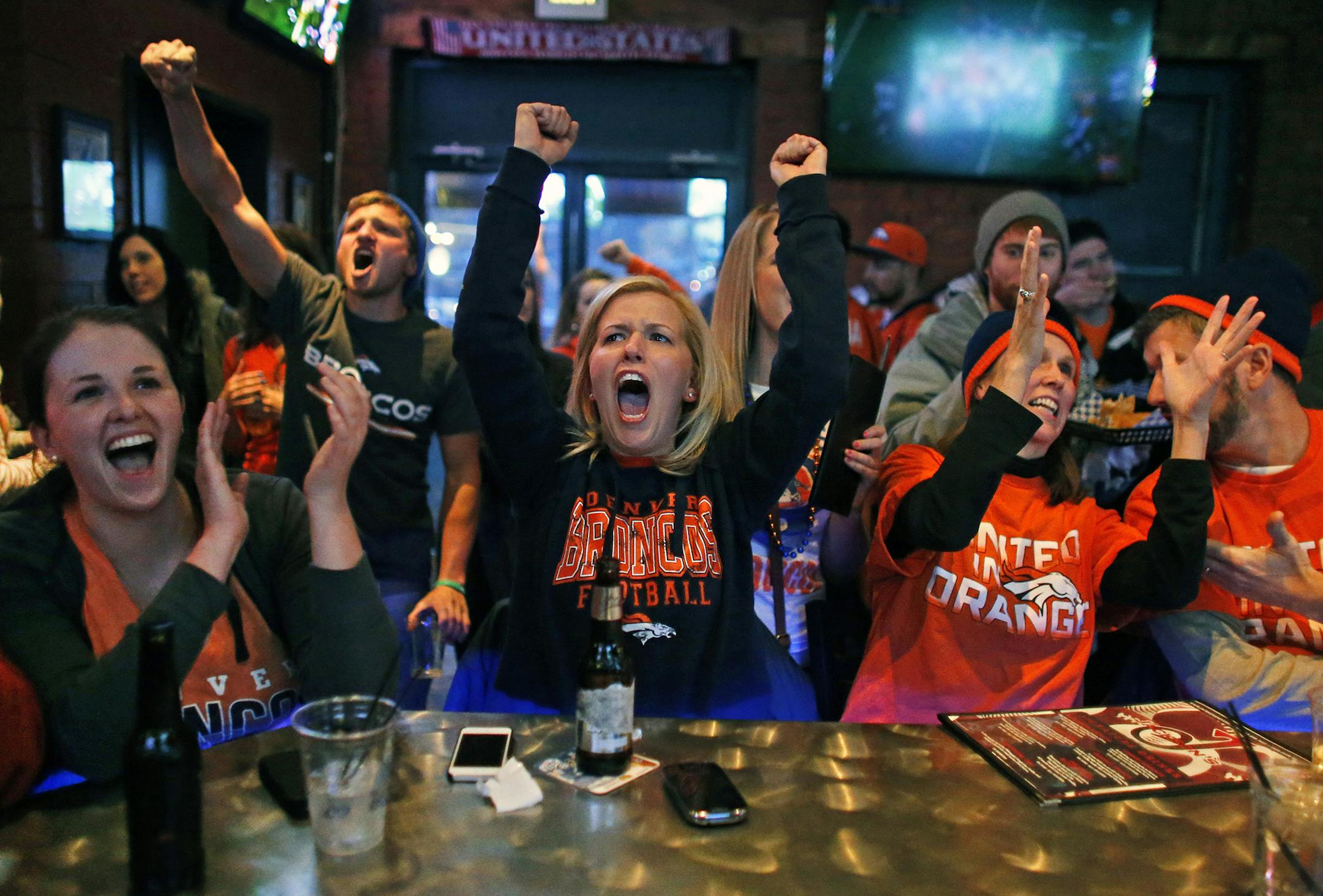 Liz Rogers, center, and her friend Caitlin O'Connor, left, celebrate as the Broncos complete a pass, while watching the first half of the Super Bowl against the Seahawks inside Jackson's, a sports bar and grill in Denver, Sunday, Feb. 2, 2014. (AP Photo/Brennan Linsley) ORG XMIT: COBL101