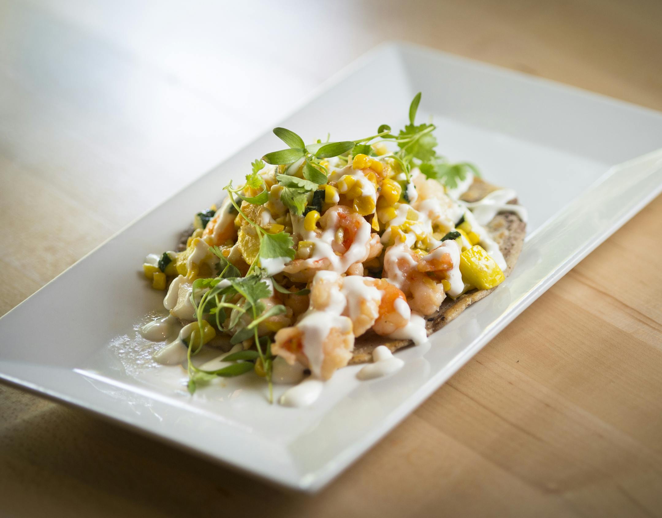 Shrimp and scallops with roasted sweet corn, squash, zucchini and cr&#xe8;me fra&#xee;che, served on a handmade tortilla.
