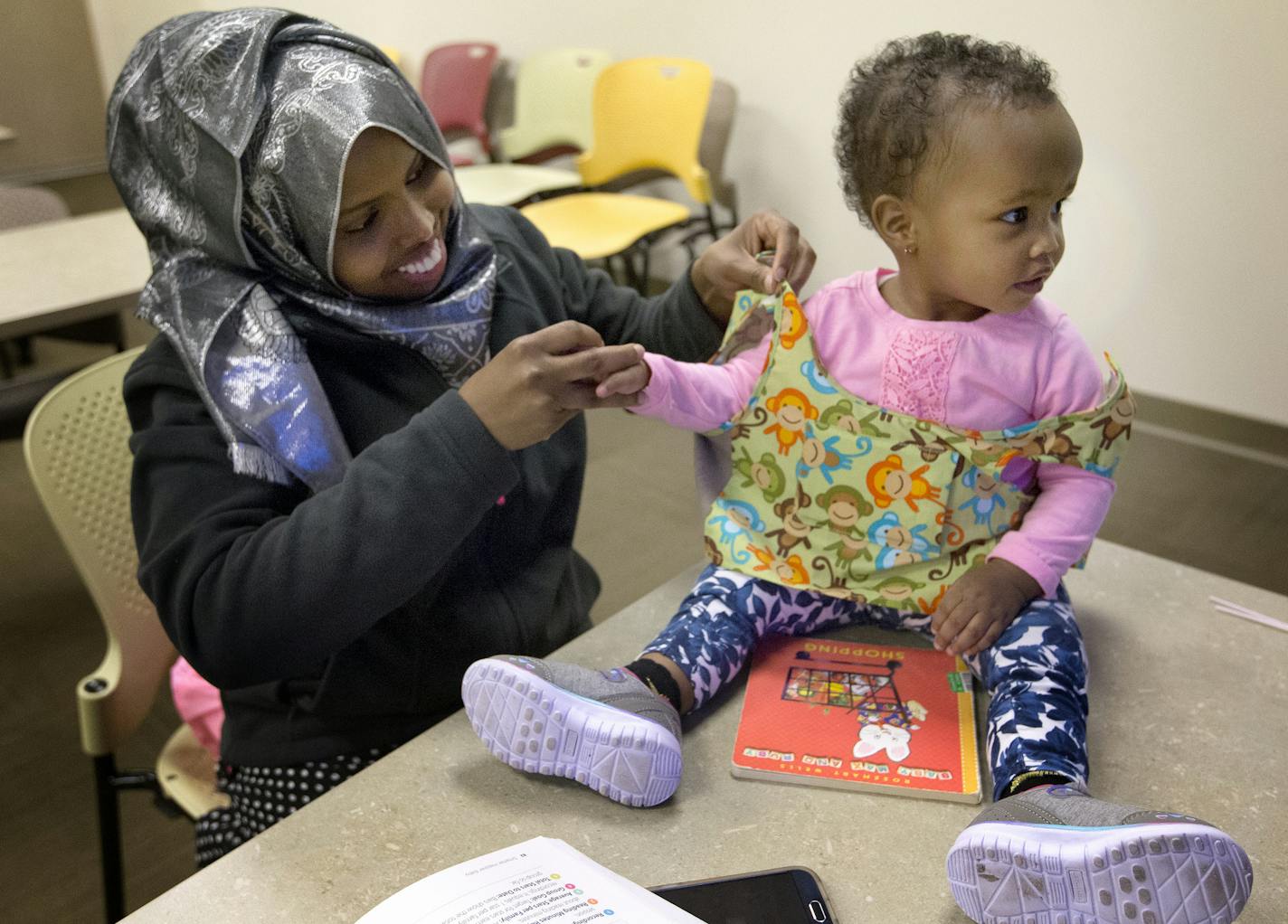 Foos Ahmed placed a special vest on her daughter Shaima Abdulle, 15-months. The vest holds a device that monitors the frequency of communication between a parent and child. ] CARLOS GONZALEZ cgonzalez@startribune.com - April 27, 2016, Plymouth, MN, The Wayzata school district is piloting a program to help early learners talk and read more at home to help improve talk between parents and children, because more interactions between parents and their babies can lead to higher IQs and vocabularies f