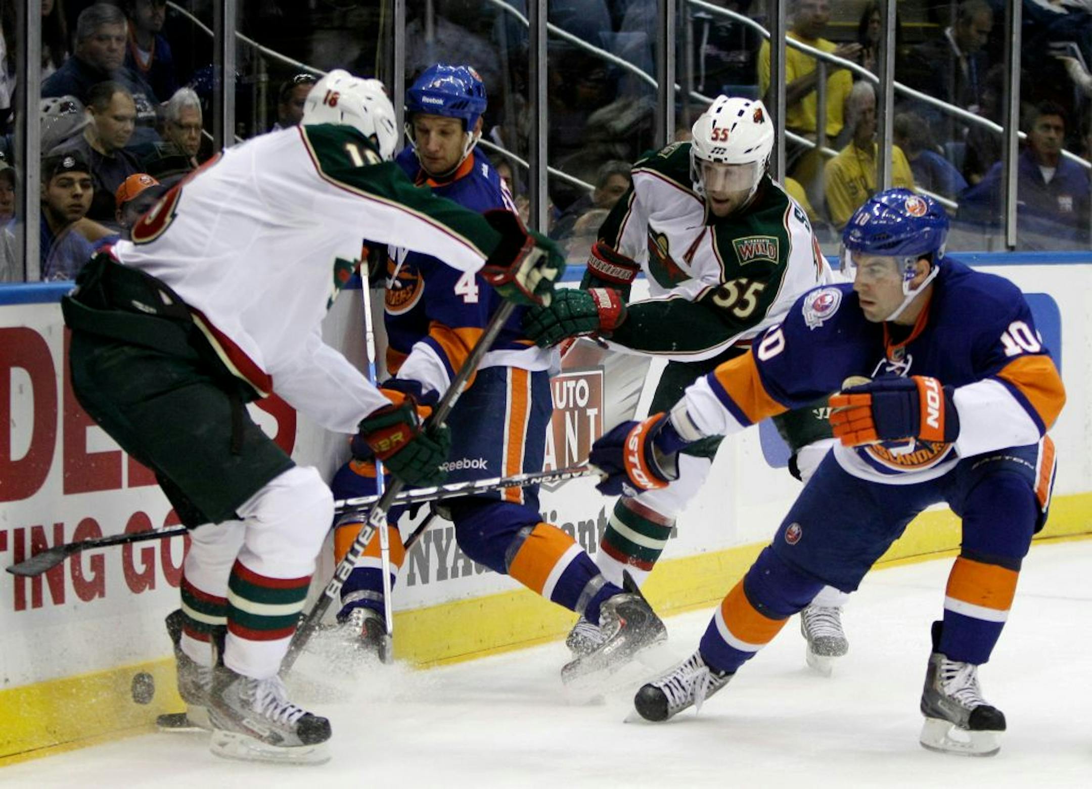 Minnesota's Devin Setoguchi (10), left, and Nick Schultz (55) fight for the puck with New York Islanders defenseman Mark Eaton (4) and defenseman Mike Mottau (10).