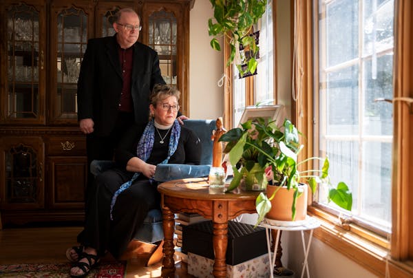 Michael and Dana Strande look out the window of their Woodbury home next to a collection of items and plants that pay tribute to their late daughter A
