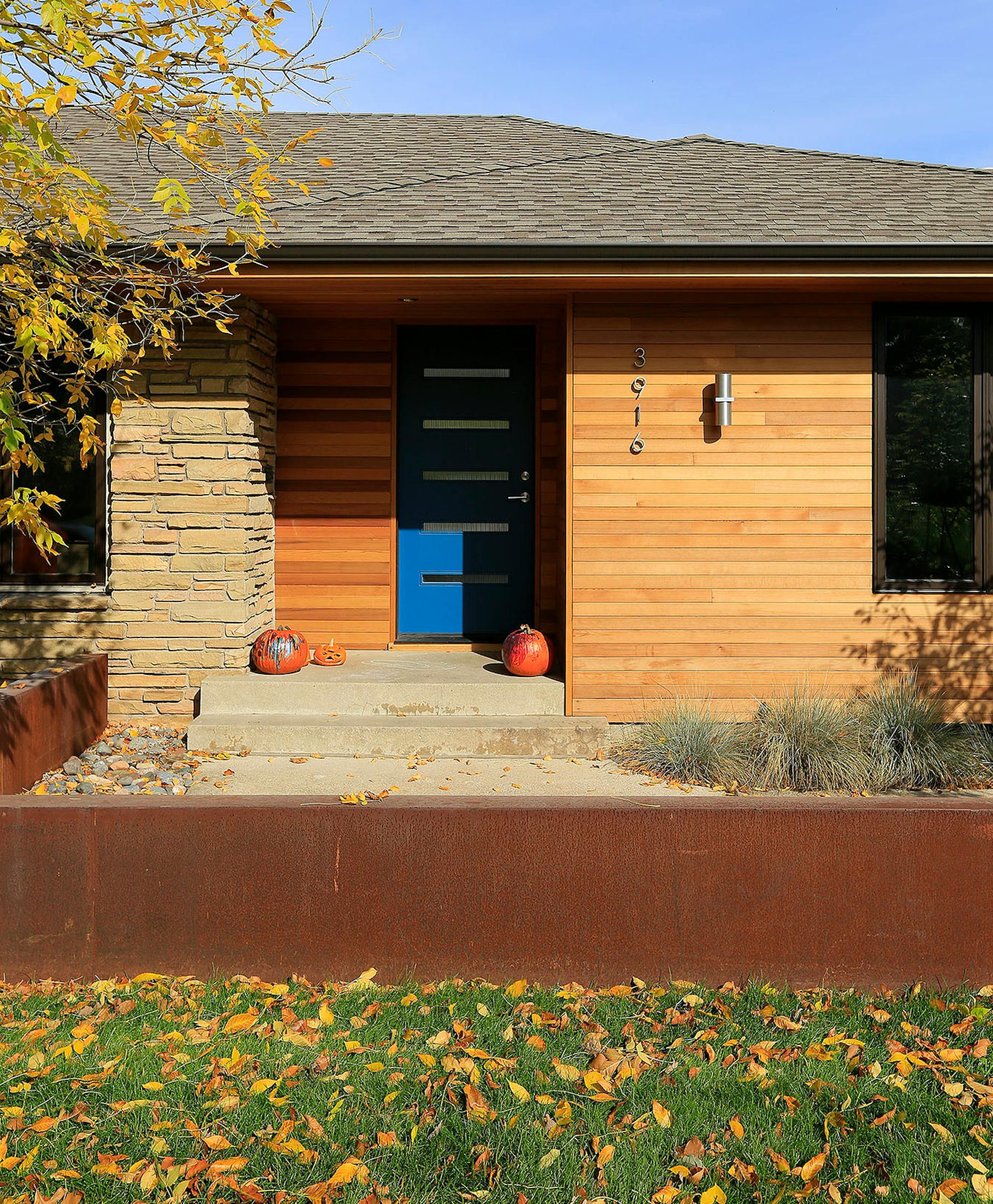 The blue painted door stands out in the front entry. A sleek steel Corten wall borders the sidewalk.