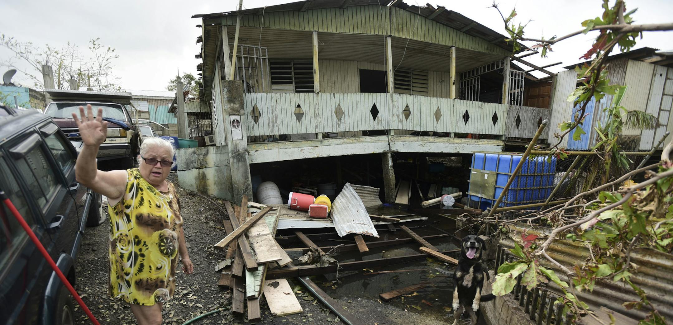 Norma Rios stands in front of her destroyed house in the aftermath of Hurricane Maria, in Catano, Puerto Rico, Wednesday, Sept. 27, 2017. Many are waiting for help from anyone from the federal or Puerto Rican government. But the scope of the devastation is so broad, and the relief effort so concentrated in San Juan, that many people from outside the capital say they have received little to no help. (AP Photo/Carlos Giusti)