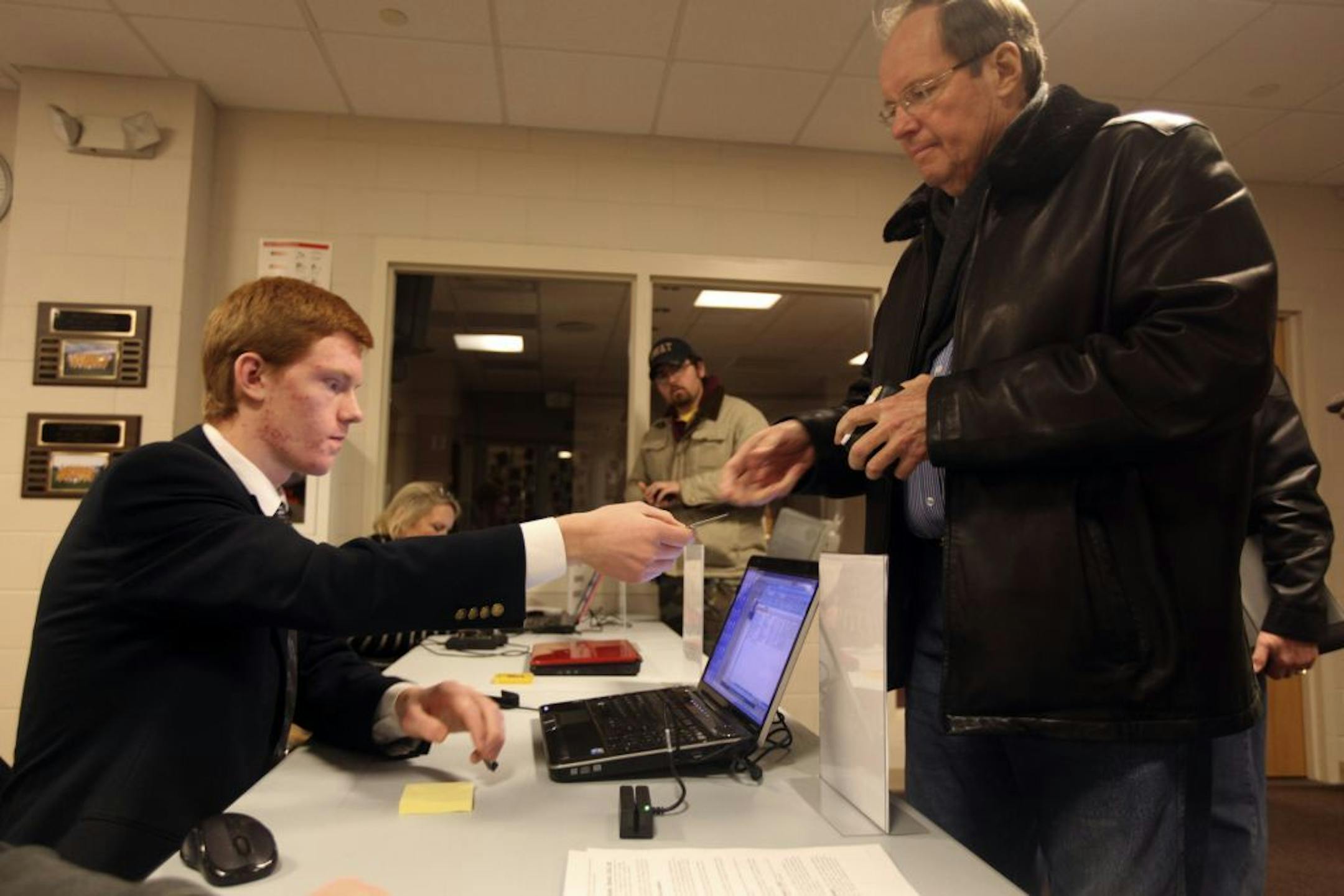 Henry Stachyra Jr., left, returns John Luoma's identification after scanning it at the Republican caucus at Rutherford Elementary School in Stillwater Minnesota, on Tuesday, February 7, 2012, amid Minnesota's Republican caucuses.