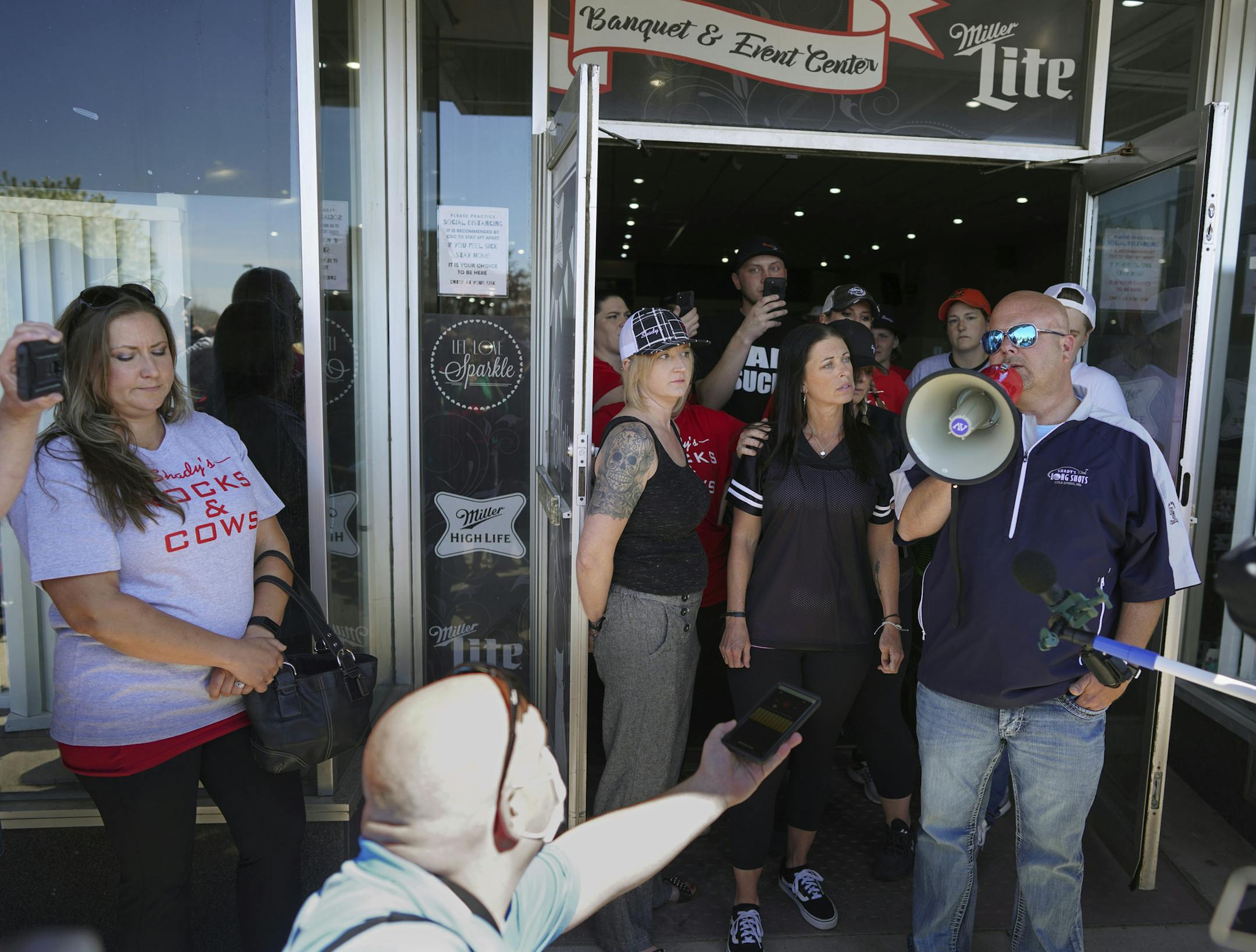 Kris Schiffler, right, the owner of Shady's Hometown Tavern in Albany, Minn. tells supporters outside his business that he's not opening his bar and grill Monday, May 18, 2020, on the advice of his attorney, after getting a call from Minnesota Attorney General Keith Ellison. (Brian Peterson/Star Tribune via AP)