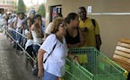 FILE - In this Sept. 25, 2017, file photo, people wait in line outside a San Juan grocery store to buy food after Hurricane Maria.