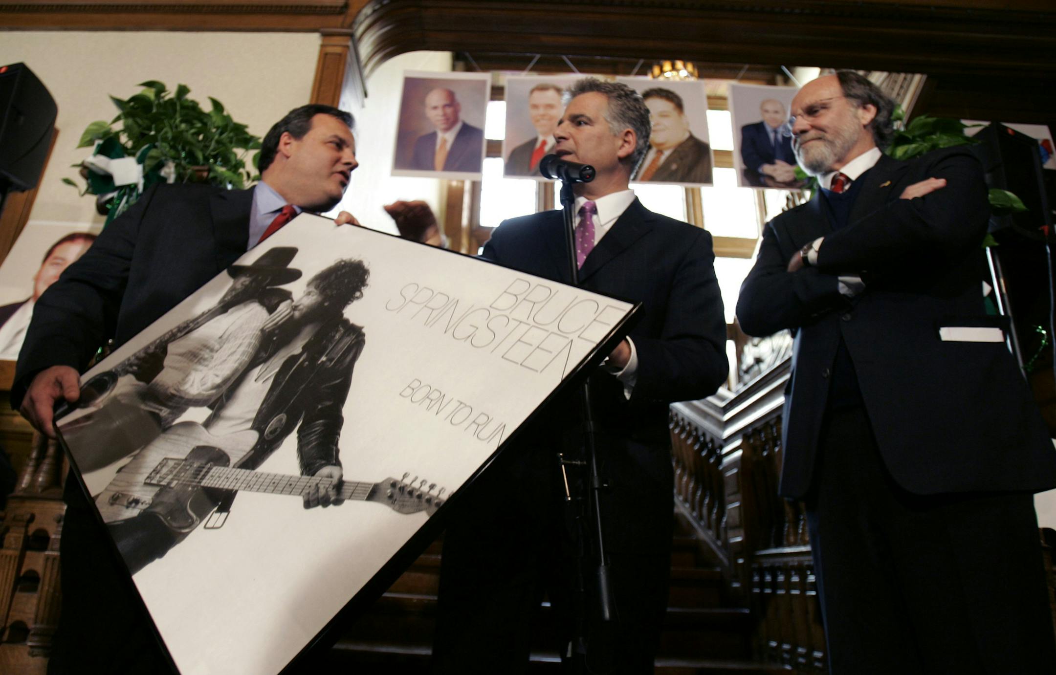 New Jersey Gov. Jon Corzine, right, watches as Christopher Christie, left,who is seeking the Republican gubernatorial nomination, holds a Bruce Springsteen poster he was given by Steve Adubato, Jr., center, at the annual North Ward Center's St. Patrick's and St. Joseph's Day celebration in Newark, N.J., Wednesday, March 25, 2009. (AP Photo/Mike Derer) ORG XMIT: NJMD105