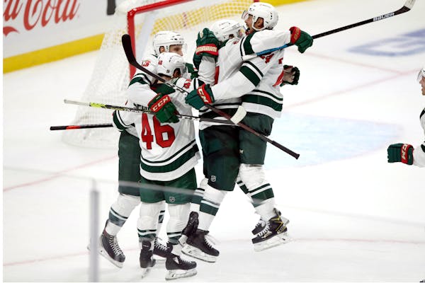 Minnesota Wild defenseman Mathew Dumba, right, leaps into the arms of left wing Kirill Kaprizov, second from right, after an overtime goal against the