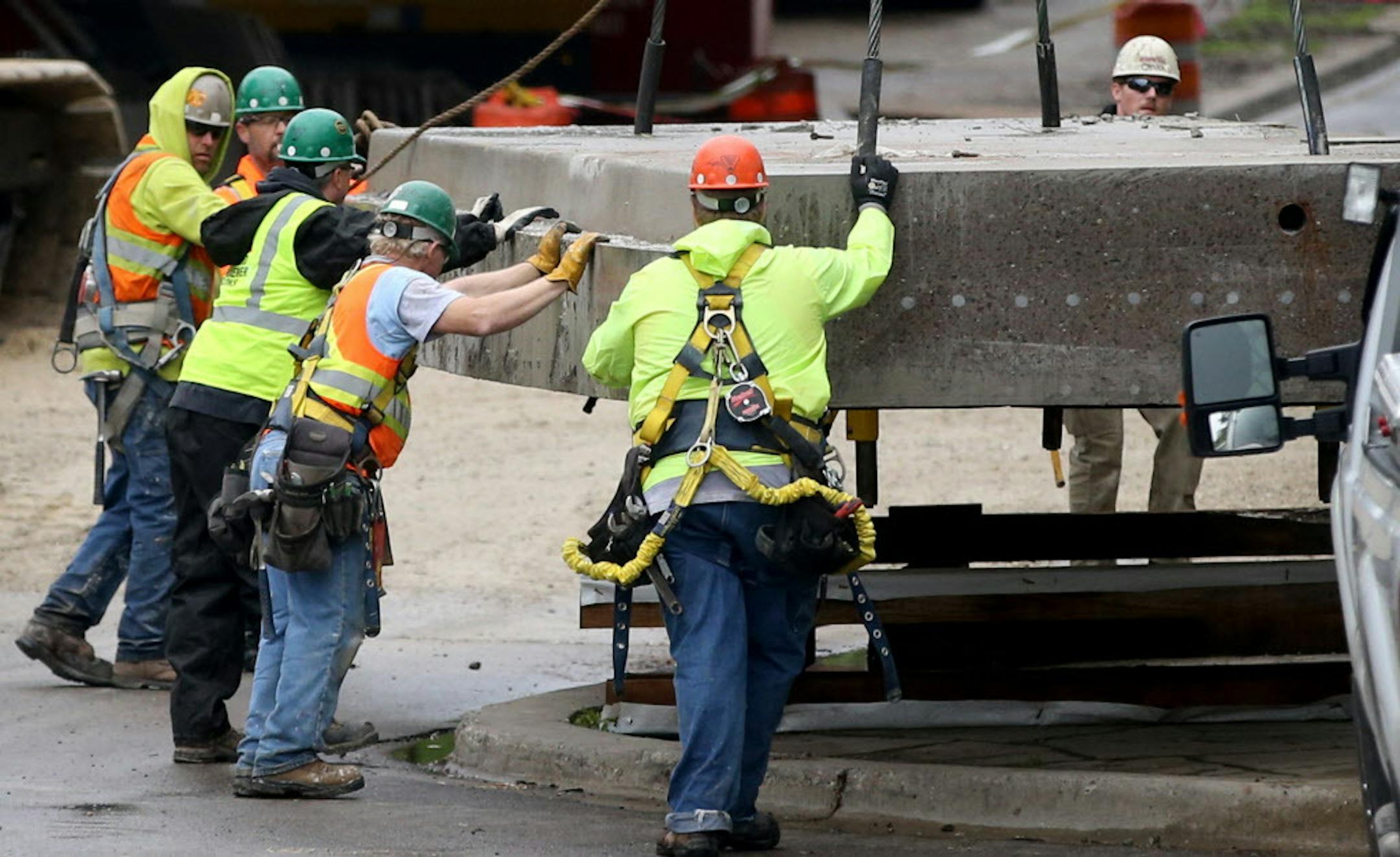 Construction workers help guide a 12 foot by 28 foot roadway panel down from the nearby Franklin Avenue Bridge after the concrete slab was sawed out of the bridge roadway Tuesday, May 10, 2016, in Minneapolis MN. The piece weighed about 25 plus tons or about 13 times what a typical motor vehicle weighs. Construction on the bridge, which began with bridge undercarriage repair in February of 2015, is expected to be completed by June of 2017. The bridge will reopen for traffic after Labor Day.](DAV
