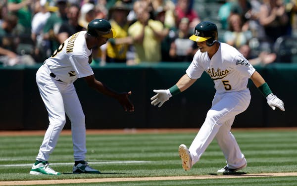 Oakland Athletics' Jake Smolinski, right, is congratulated by third base coach Ron Washington after hitting a home run off Minnesota Twins pitcher Pat