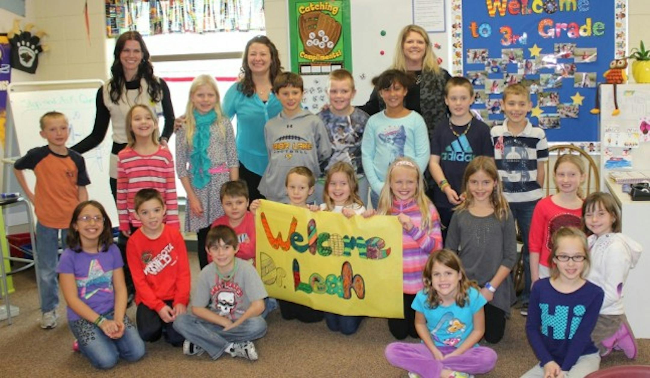 Leah Tygum, MD (back row, left), visited the third-grade classroom of patient Sophia Nelson (middle row, second from left) at Redtail Ridge Elementary School in Savage to talk about the science of sound and hearing.