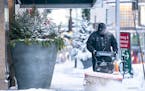Charles Zajicek used a power sweeper to clear snow off the sidewalk in downtown Minneapolis on Thursday. The Twin Cities got 8 inches of snow Wednesda