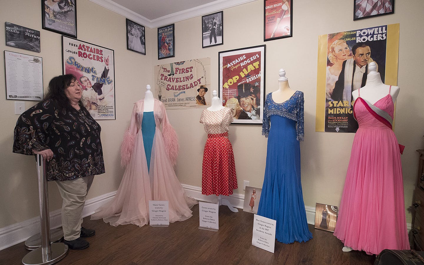 Marge Padgitt looks over a display of dresses worn by Ginger Rogers at The Ginger House museum, Birthplace of Ginger Rogers, on Aug. 23, 2018 in Independence, Mo. The blue gown was worn by Rogers at the 1967 Academy Awards. Roberta Olden, former secretary to Rogers, donated the gown and other items to Padgitt for the museum. (Tammy Ljungblad/The Kansas City Star/TNS)