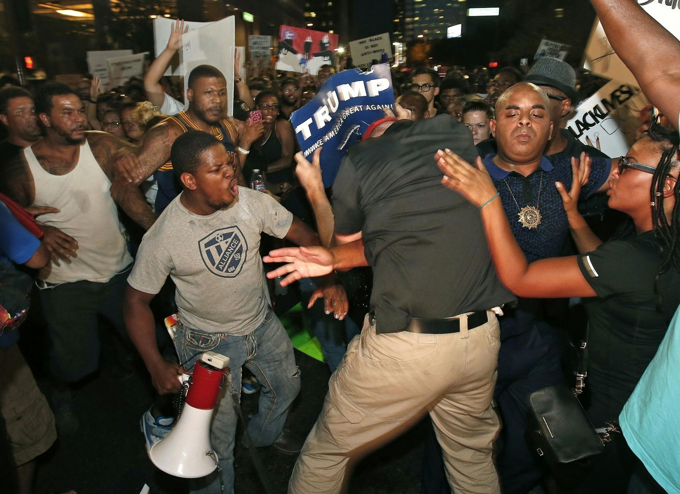 Rev. Jarrett Maupin, second from right, stands his ground as a Republican presidential candidate Donald Trump supporter, center, tries to interrupt marchers, as they take to the streets to protest against the recent fatal shootings of black men by police Friday, July 8, 2016, in Phoenix. (AP Photo/Ross D. Franklin)