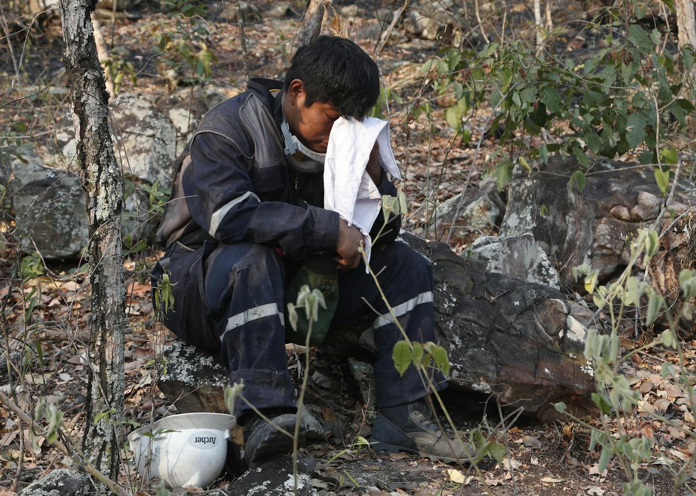 A volunteer wipes his face as he takes a break from fighting fires in the Chiquitania forest on the outskirts of Robore, Bolivia, Bolivia, Thursday, Aug. 29, 2019. While some of the fires are burning in Bolivia's share of the Amazon, the largest blazes were in the Chiquitania region of southeastern Bolivia. It's zone of dry forest, farmland and open prairies that has seen an expansion of farming and ranching in recent years. (AP Photo/Juan Karita)