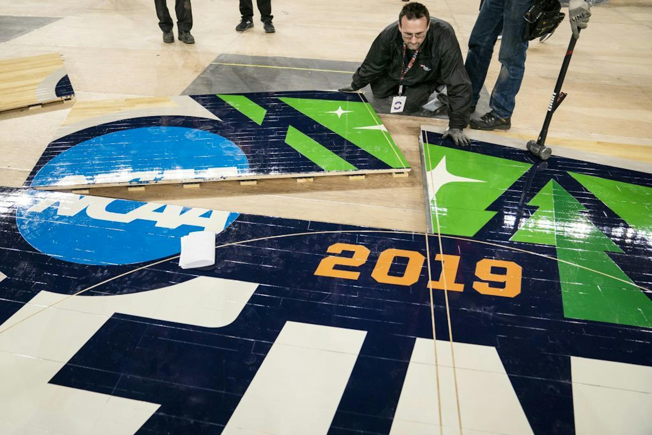 U.S. Bank Stadium operations worker Michael Stauffacher installs the official 2019 NCAA Final Four court.